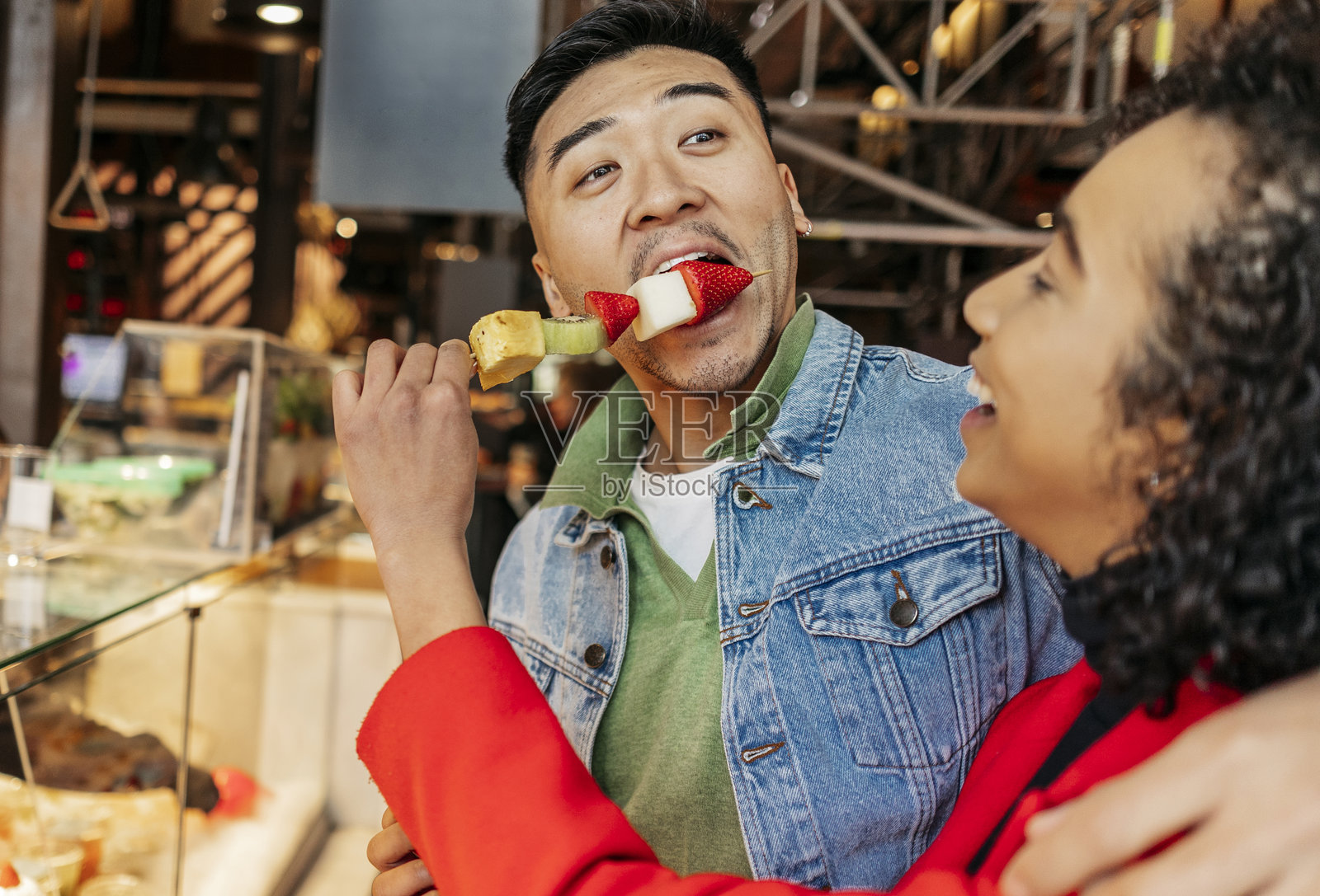 年轻的多种族情侣在情人节的市场上吃水果串照片摄影图片