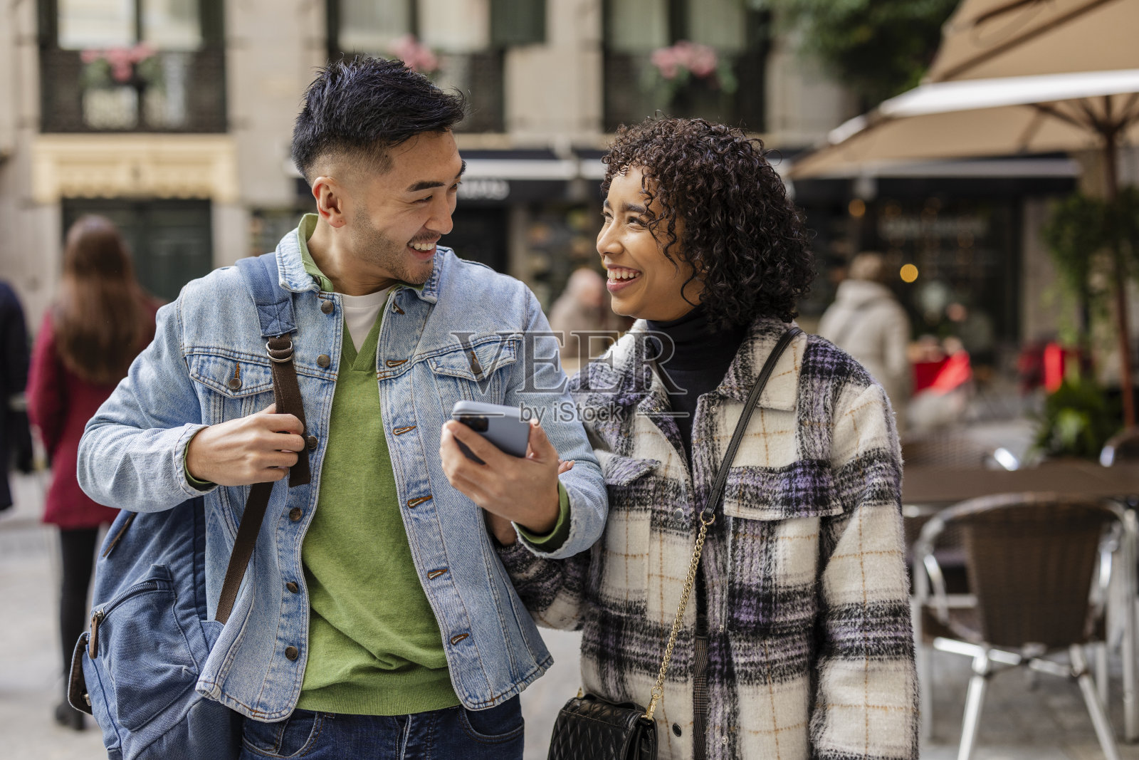 快乐的多种族情侣在街上走路时使用智能手机照片摄影图片