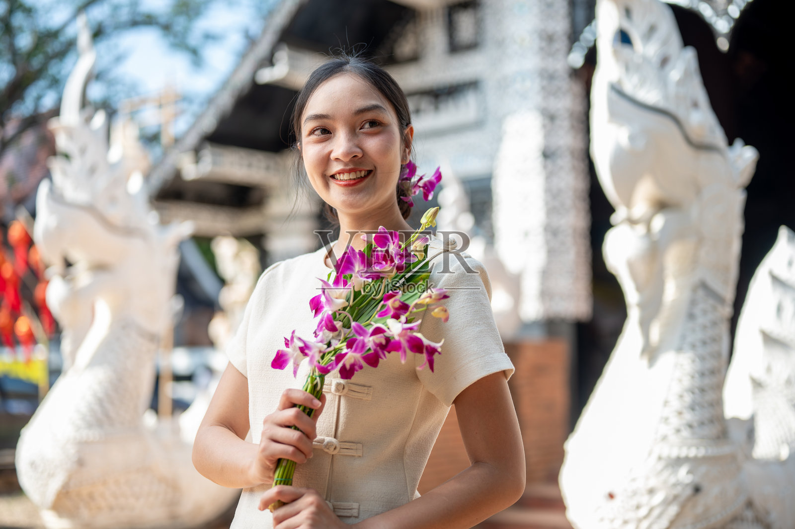 迷人的亚洲女性穿着传统的泰国兰纳服装，站在美丽的古老寺庙前。照片摄影图片