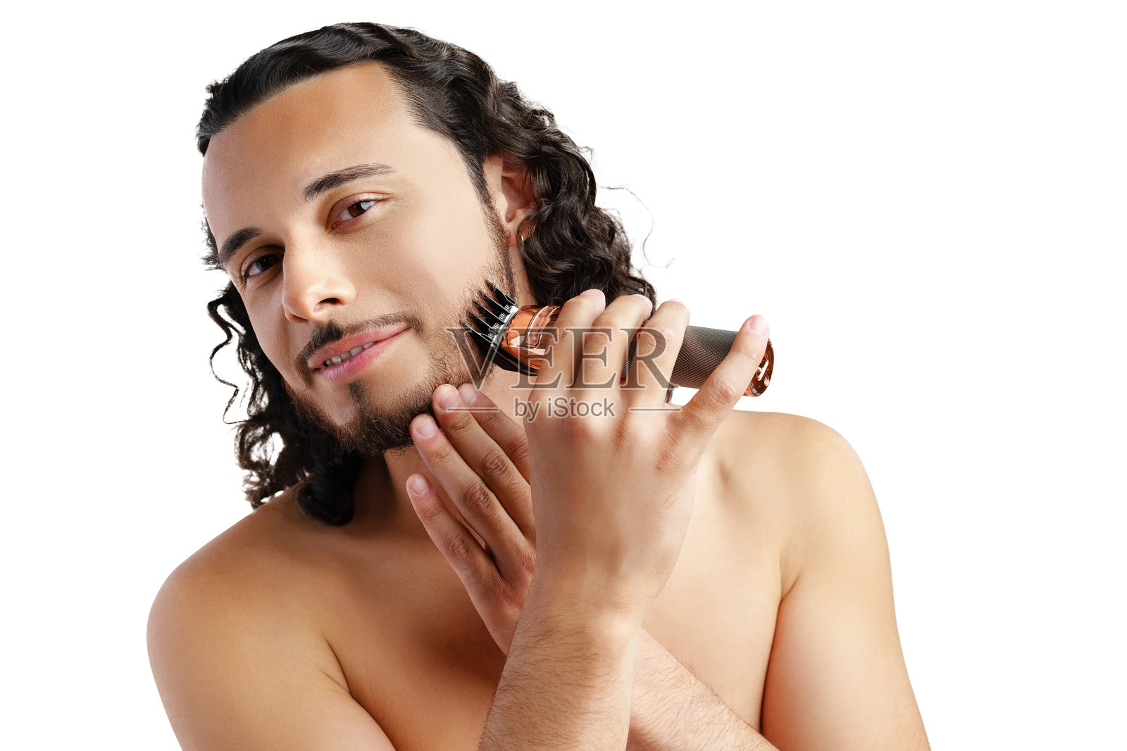 一位年轻的卷发男士正在使用电动修剪器修整他的胡须照片摄影图片