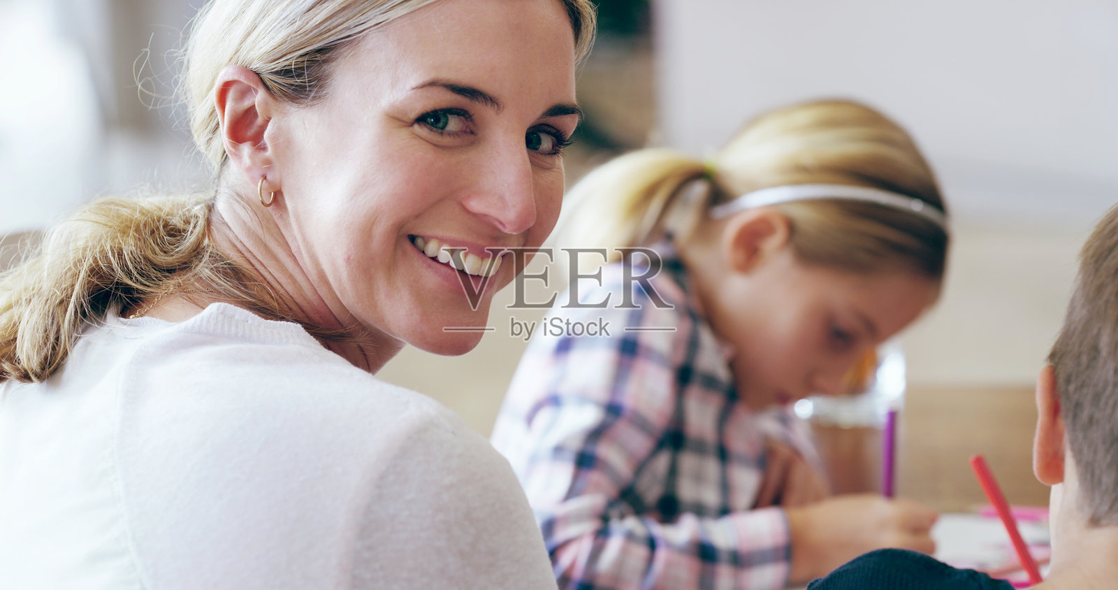 妈妈与孩子们微笑合影，帮助他们完成作业，促进发展、进步和学习。孩子们、母亲和女儿与兄弟姐妹们在西班牙的家中一起写作和学习。照片摄影图片