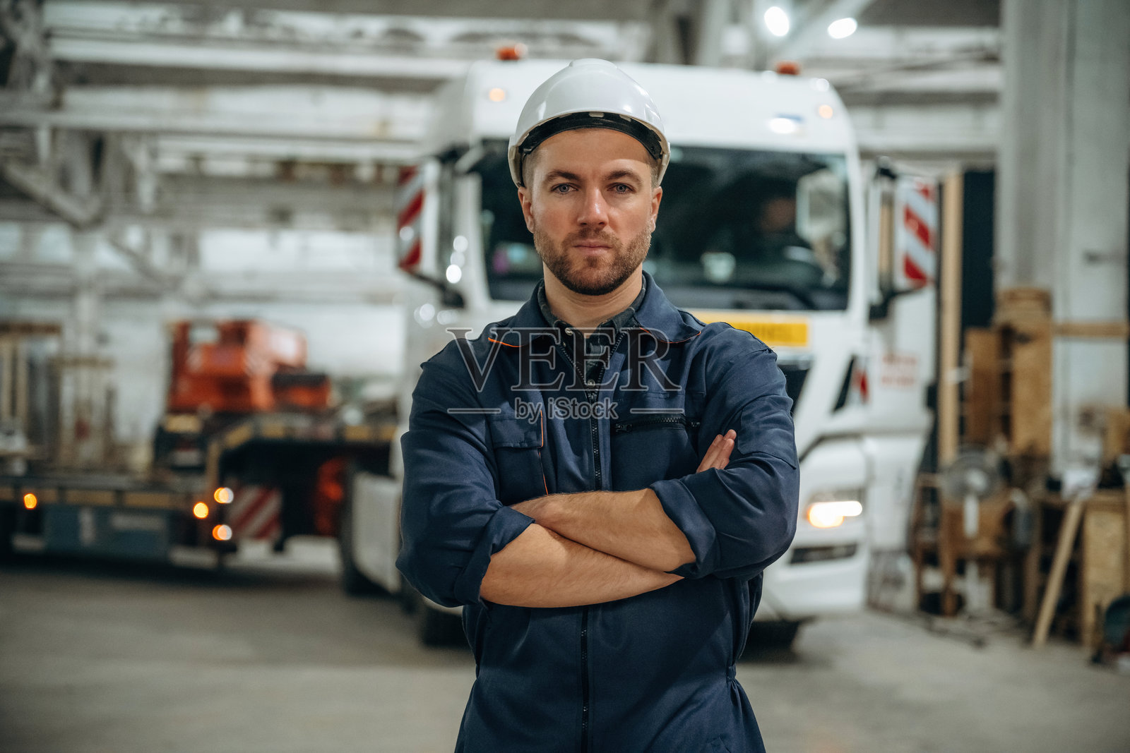 站在卡车前的男性工人在现代仓库或制造公司内。照片摄影图片