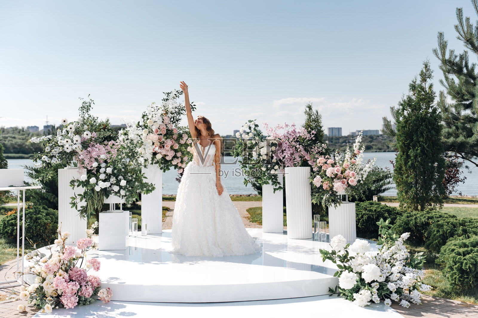 一位新娘在河岸上装饰着鲜花的婚礼仪式区域。照片摄影图片
