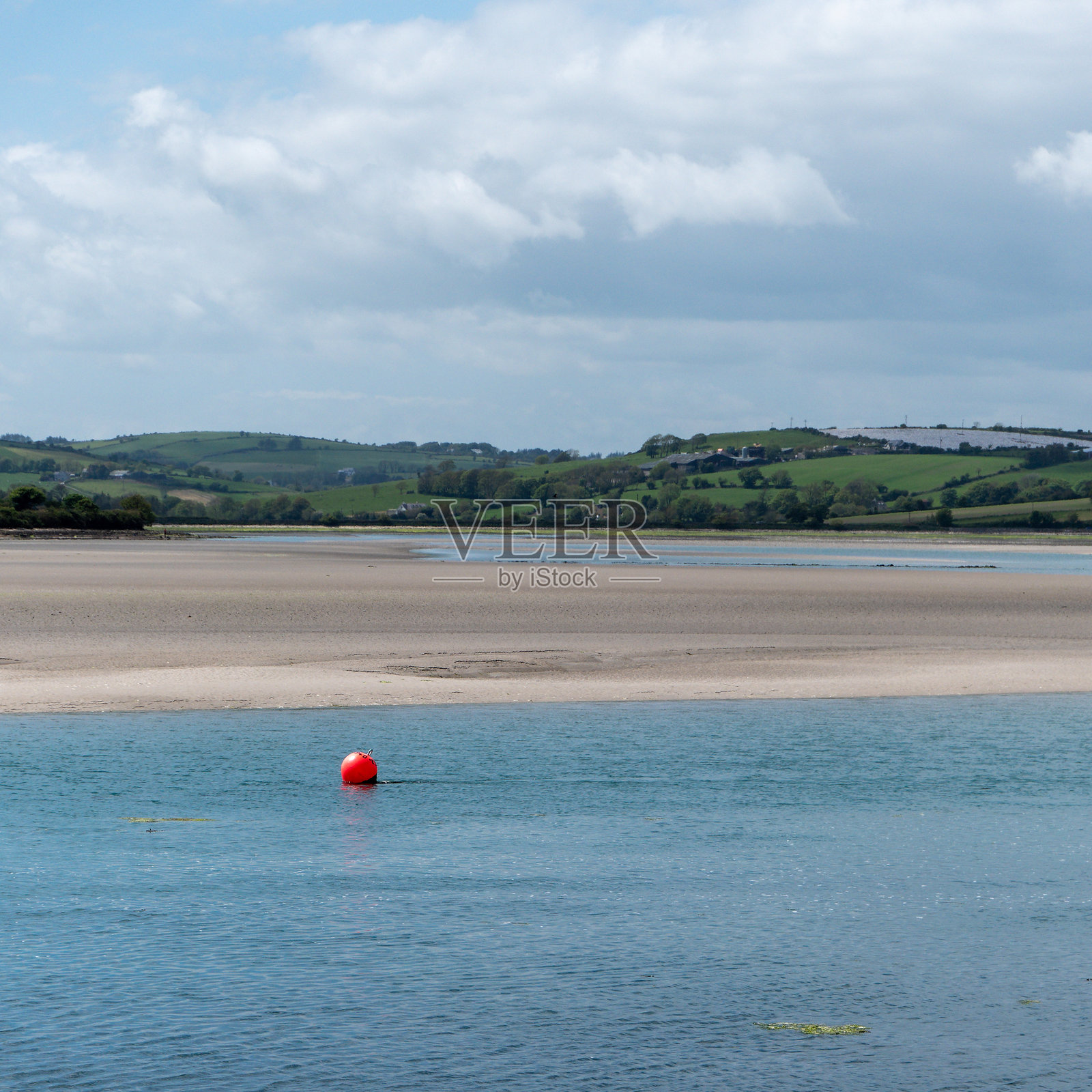 阳光明媚的日子里，水面上漂浮着一个小橙色浮标。爱尔兰海岸风景，水体。照片摄影图片