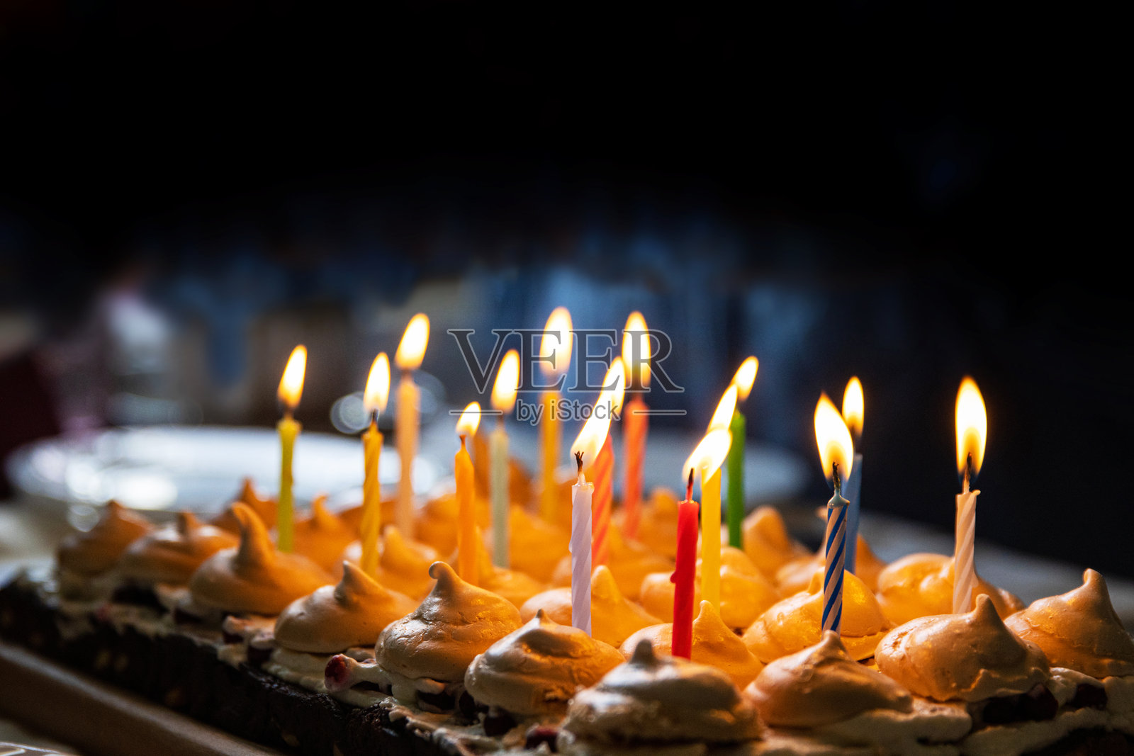 五彩缤纷的生日蛋糕，上面点缀着点燃的蜡烛和金色的蛋白霜，完美适合庆祝15周年纪念。选择性聚焦。照片摄影图片