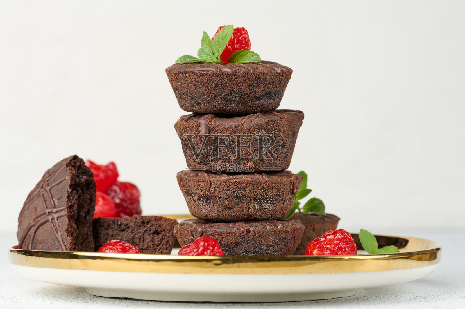 巧克力布朗尼叠放在一起，顶部装饰着红色多汁的樱桃和薄荷叶照片摄影图片
