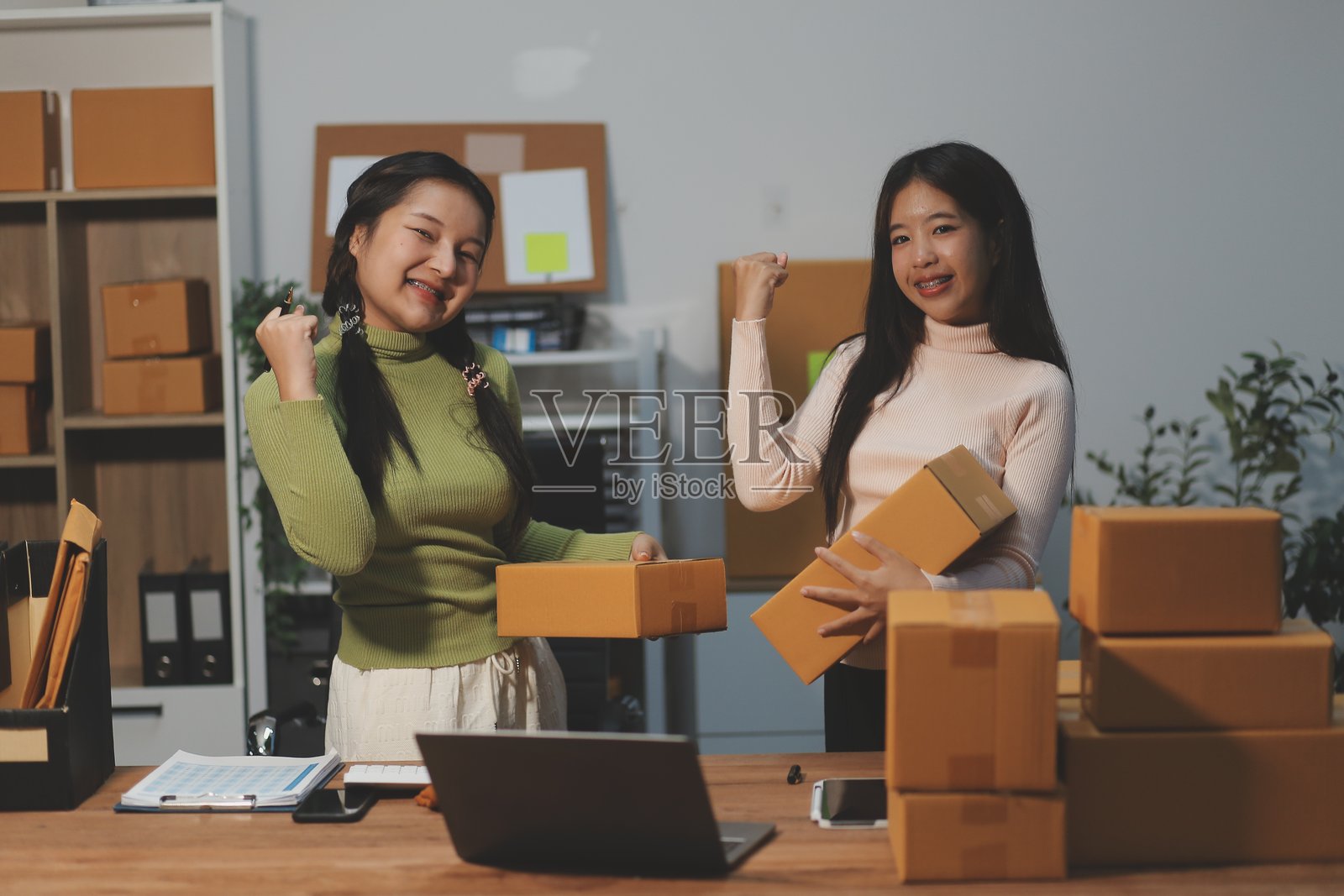 身穿围裙的亚洲女性创业者，使用笔记本电脑和箱子在线接收和审核订单，准备打包出售给客户，在线中小企业商业创意。照片摄影图片