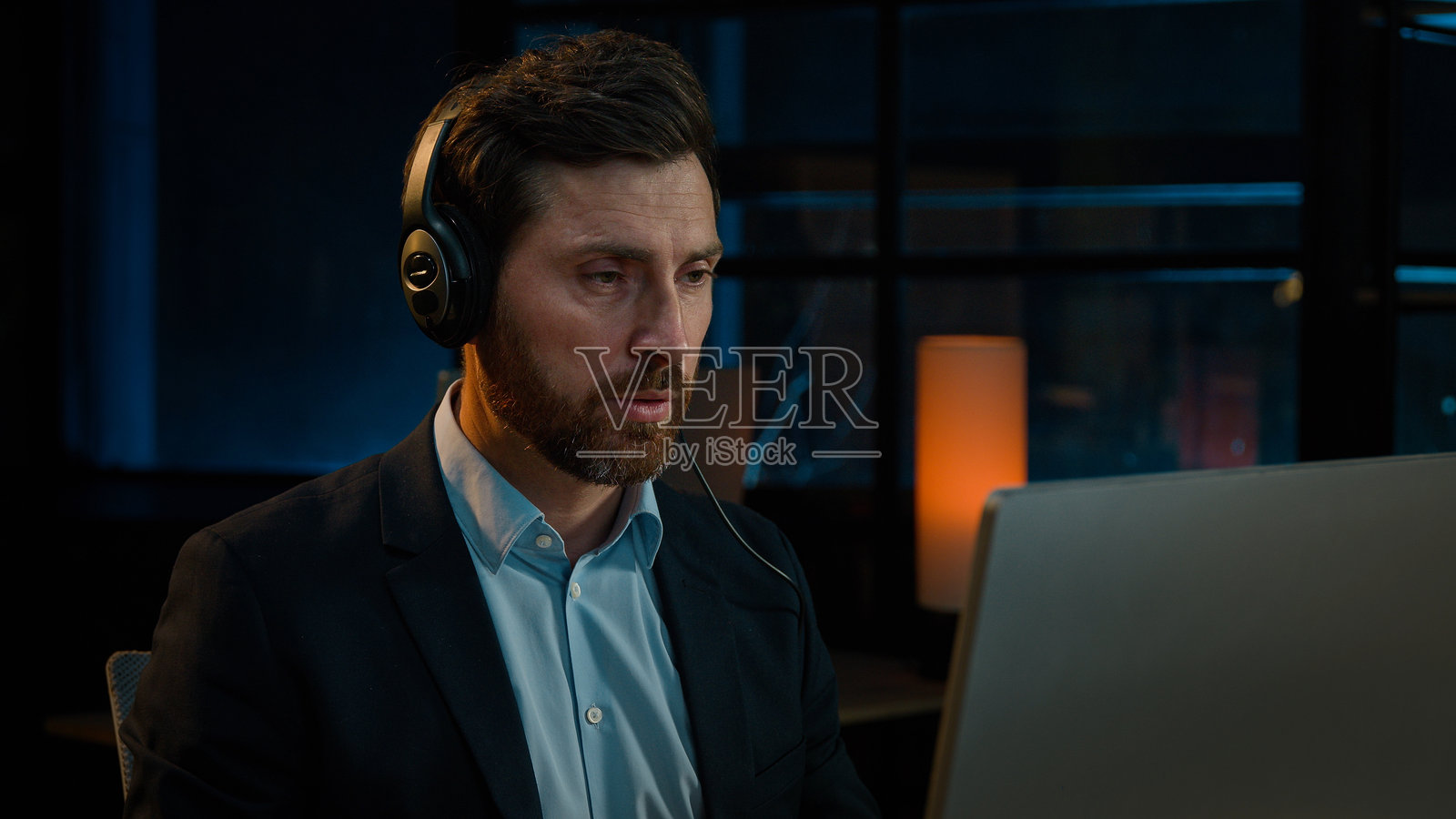 戴着耳机的商人经理在呼叫中心使用计算机耳机，与客户进行远程咨询，进行在线网络会议，属于电话营销行业的白人男性，40多岁。照片摄影图片