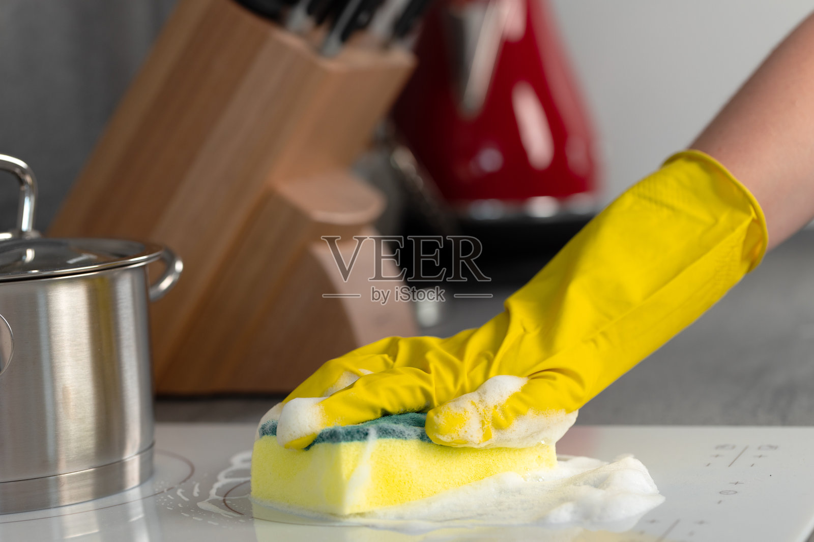 女性戴着黄色手套用海绵清洁电炉照片摄影图片