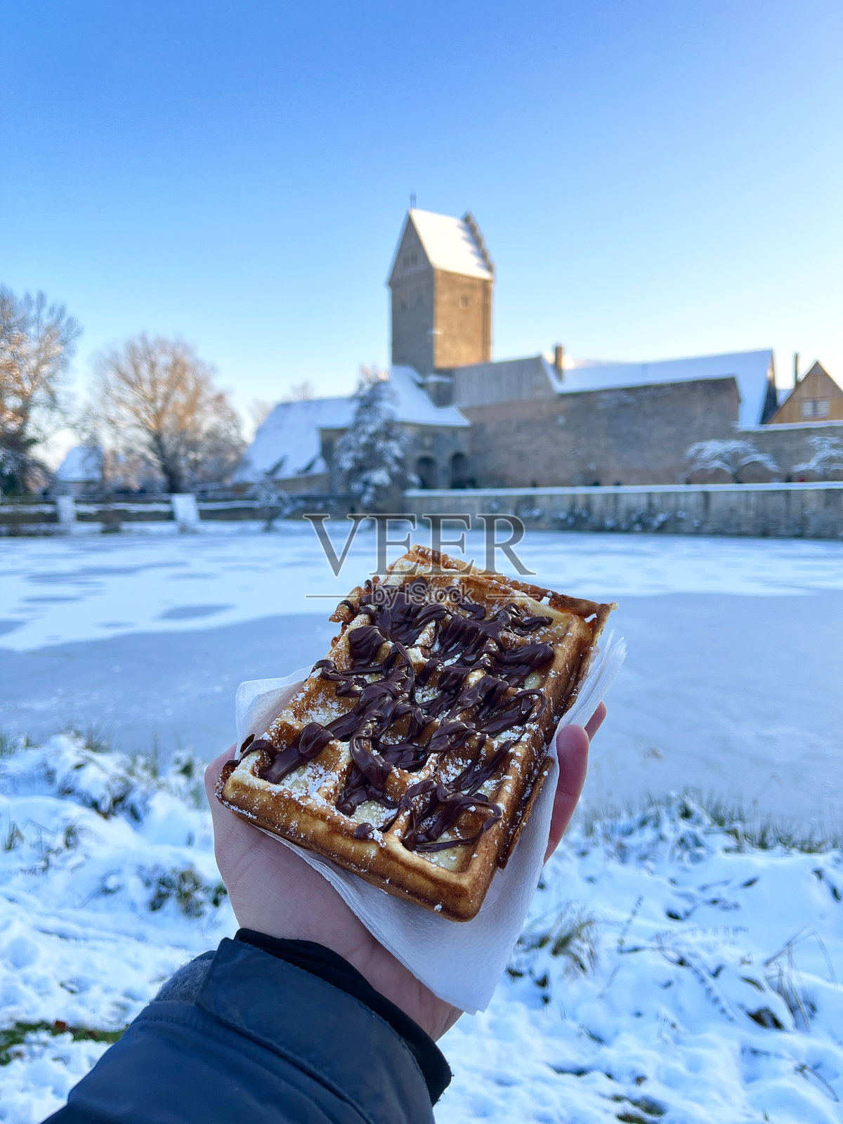 游客在德国丁克尔斯比尔圣诞市场手持巧克力和糖粉华夫饼照片摄影图片