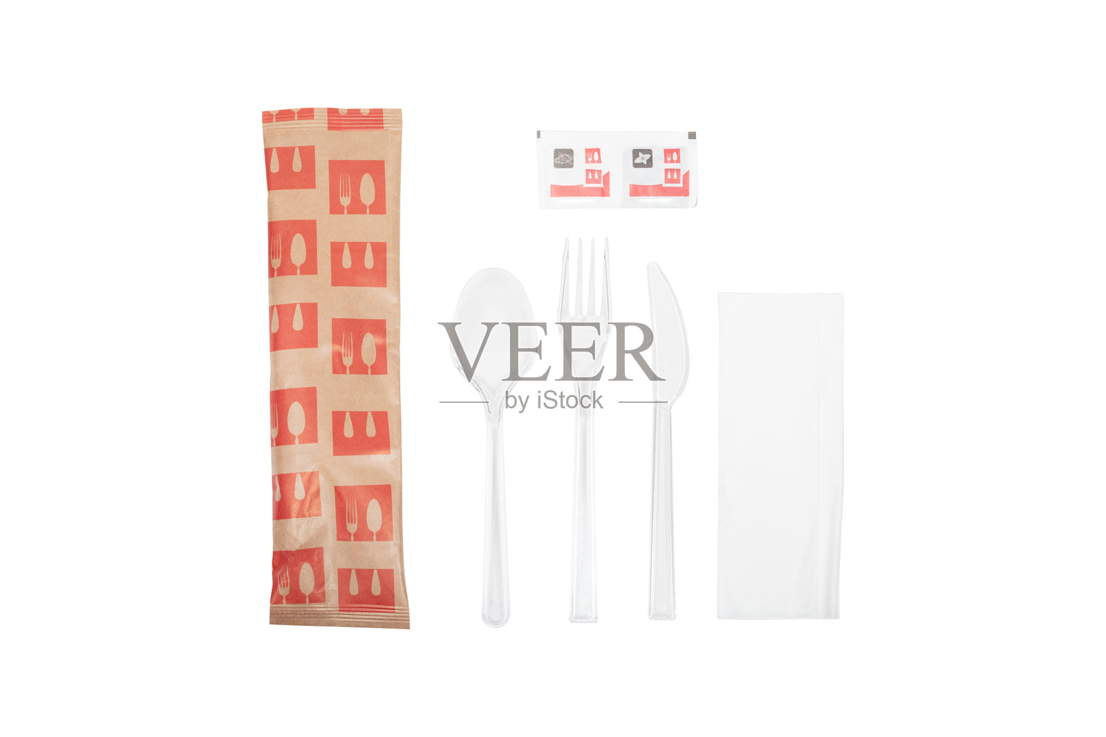 透明包装中的一次性塑料餐具套装，包括叉子、勺子、刀子，以及餐巾纸和调味包，背景为白色，餐厅用品。照片摄影图片