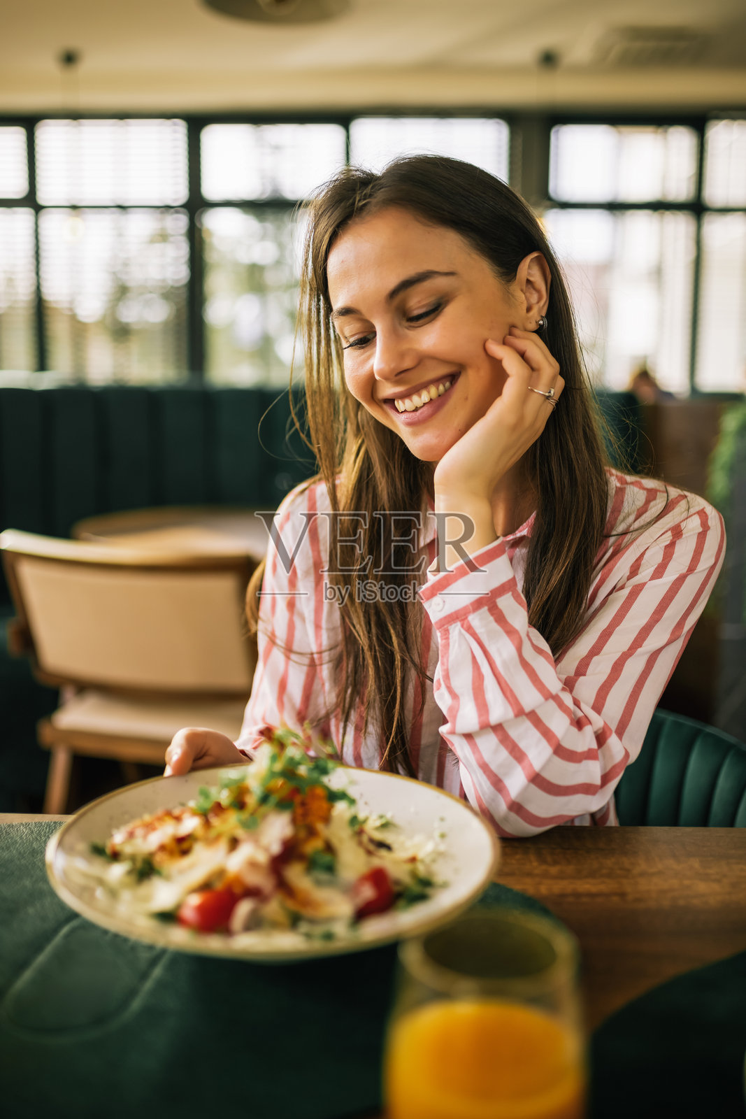 美丽的女人在餐厅里吃凯撒沙拉。照片摄影图片