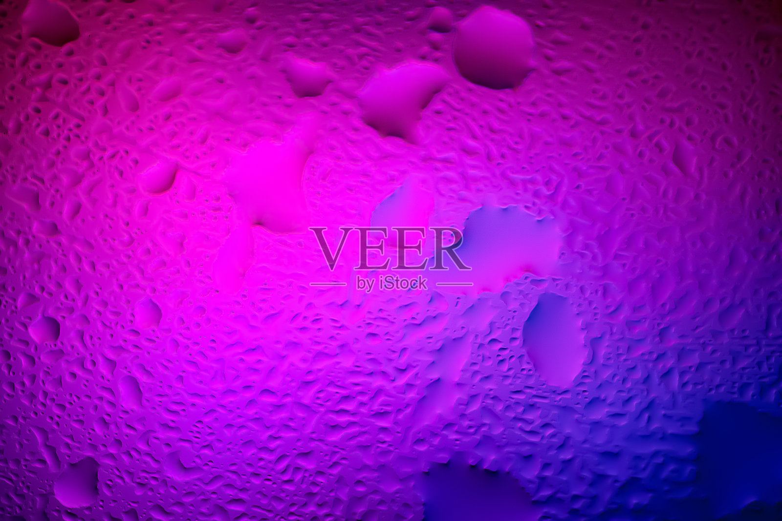 抽象背景。通过湿玻璃的彩色柔和渐变和镜头光晕的模糊抽象图像。玻璃上水滴的纹理。照片摄影图片