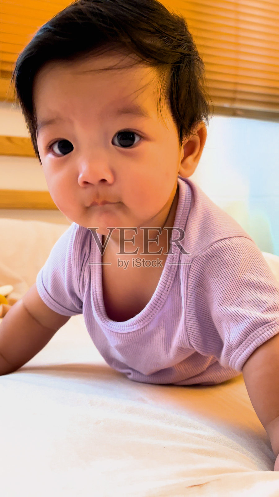 亚洲男婴在床上学习爬行。照片摄影图片