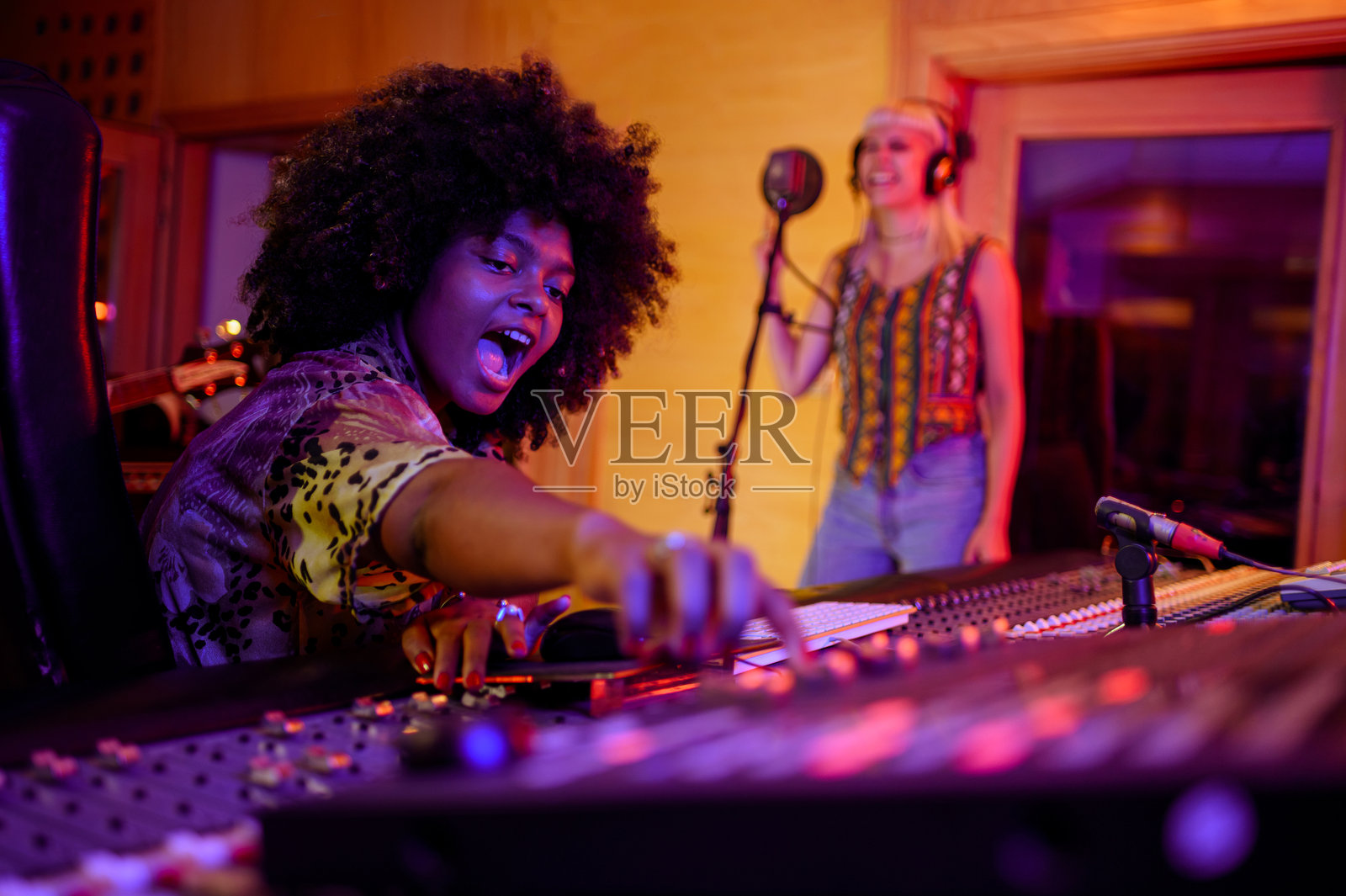 兴奋的多元化女性制作人与频道混音器录制歌手。照片摄影图片