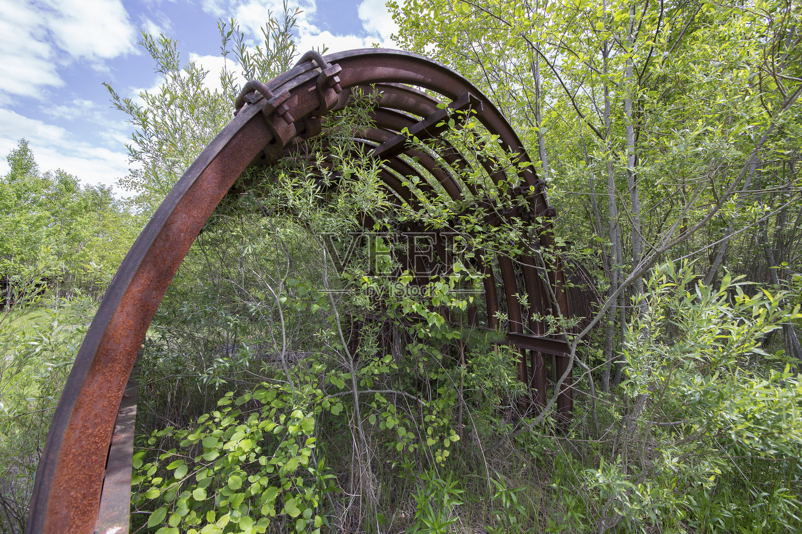 一堆生锈的废弃物和被大自然吞没的旧矿设备照片摄影图片