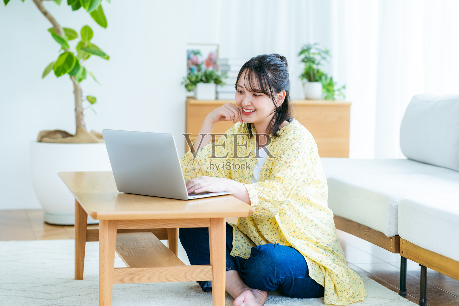 年轻女性在客厅里看着笔记本电脑照片摄影图片