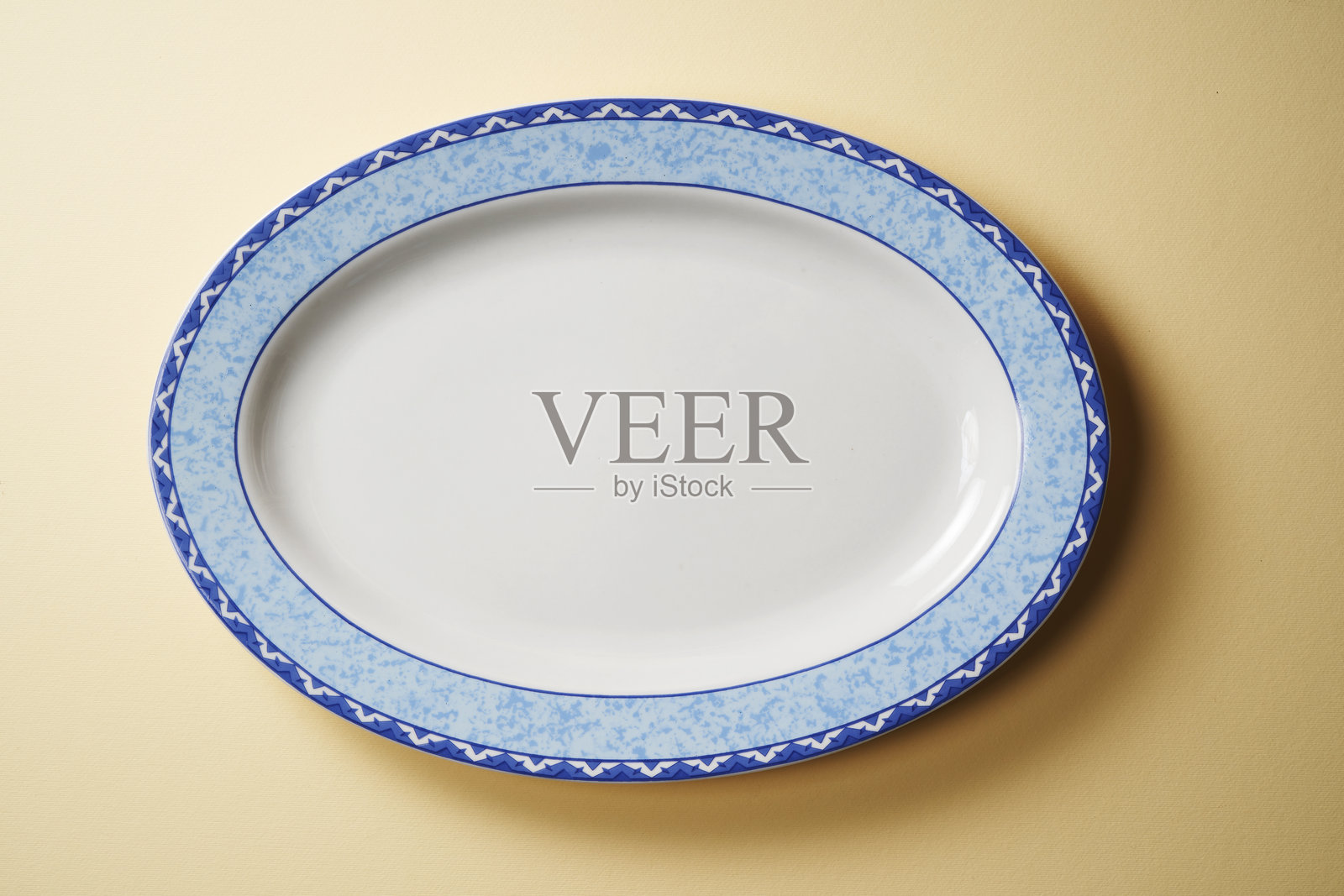 白色空椭圆形盘子置于黄色背景上照片摄影图片