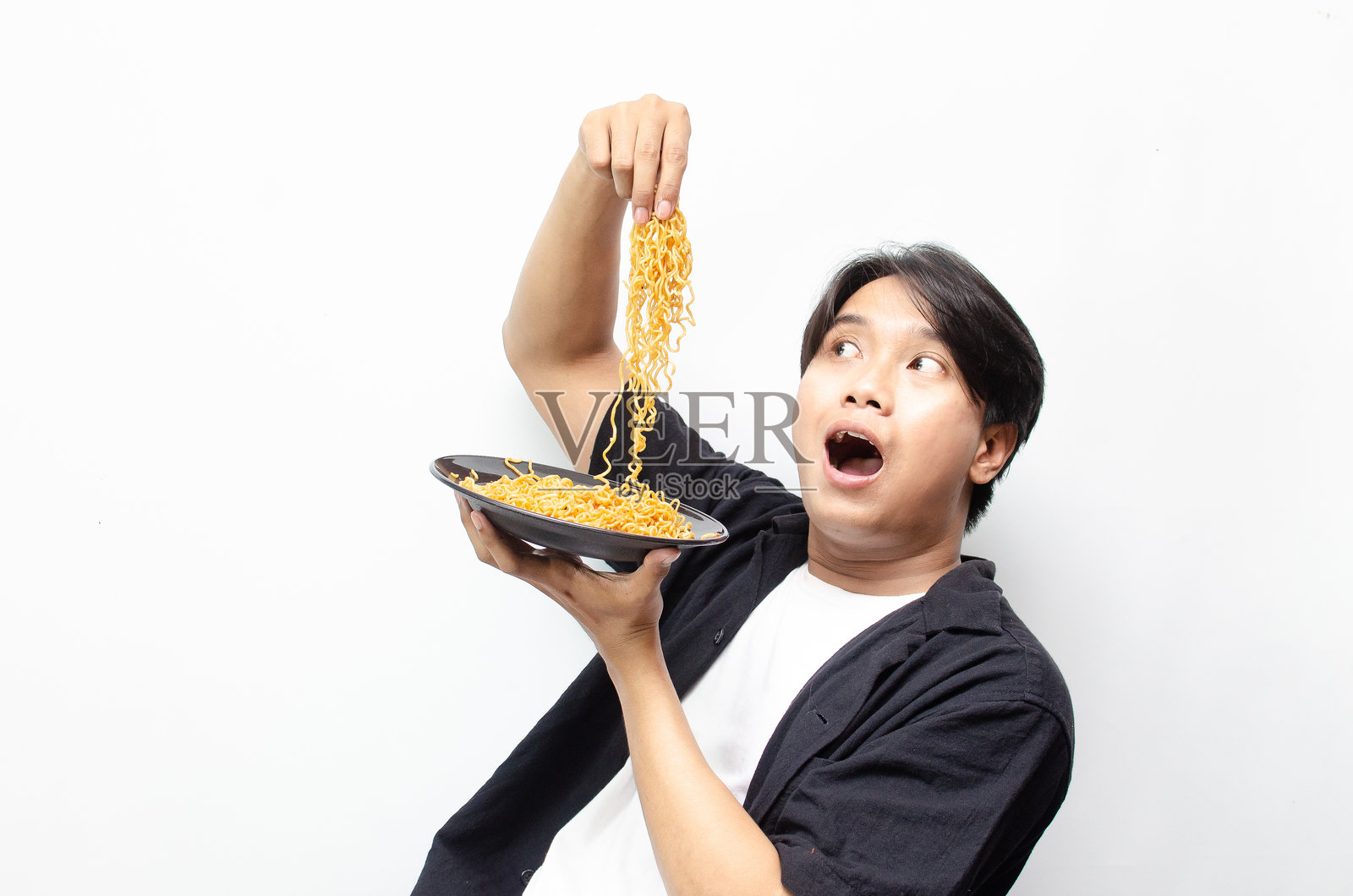 年轻的亚洲男子享受着满嘴面条的炸面条。照片摄影图片