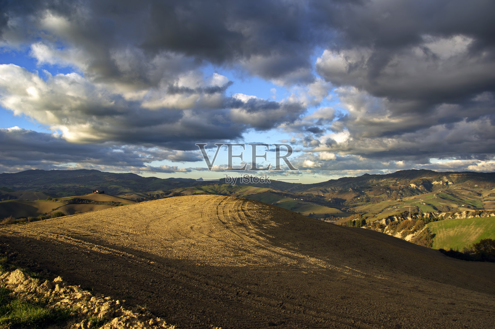 蒙特费尔特罗的丘陵风景，金色时光下的田野与多云的天空相映成趣照片摄影图片