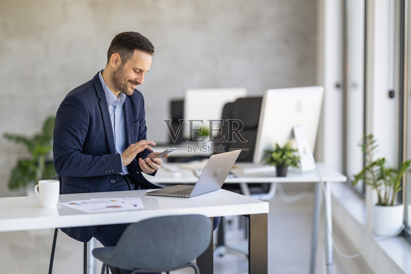 专业男士在现代办公室使用智能手机和笔记本电脑照片摄影图片