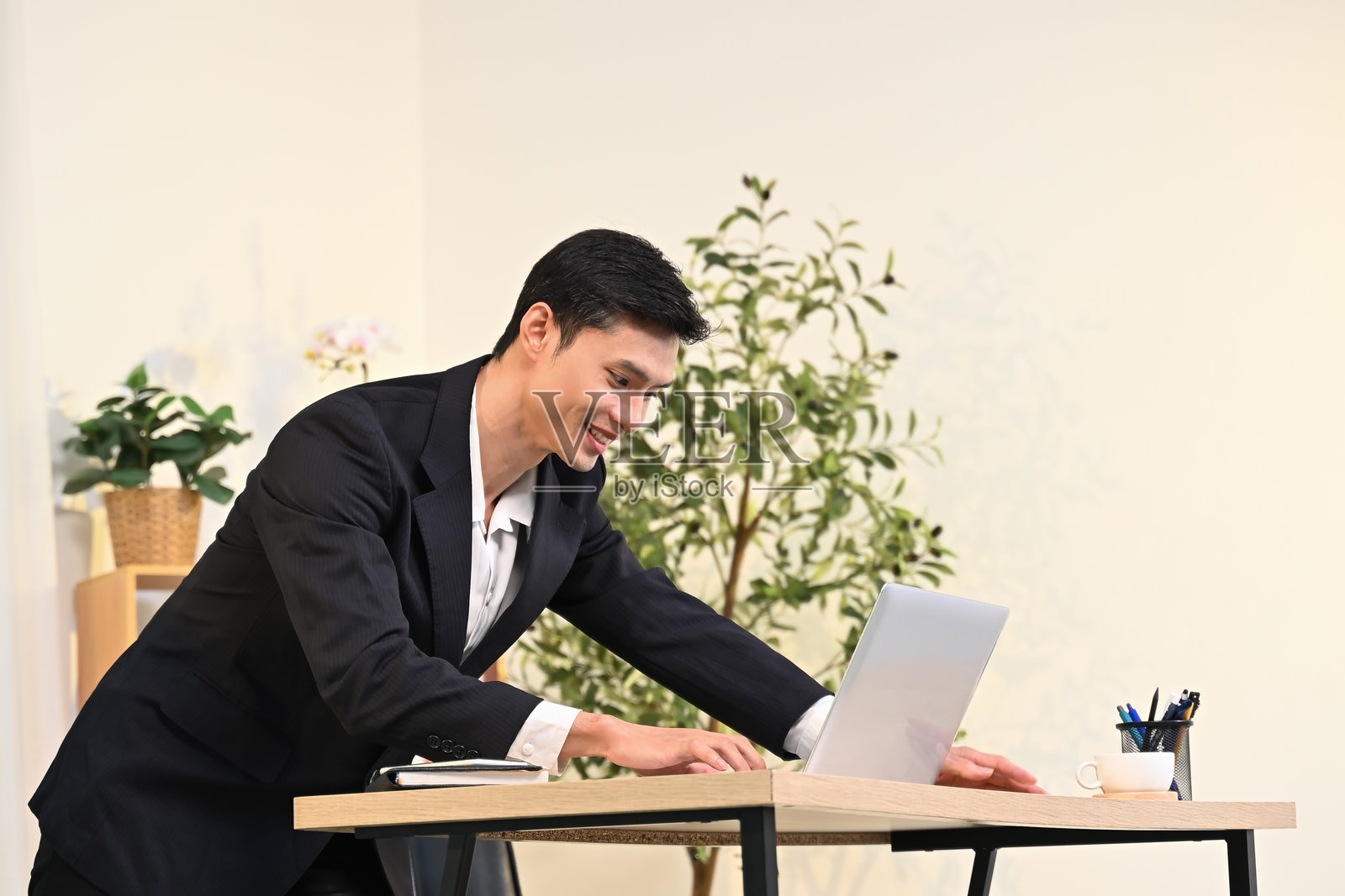 微笑的亚洲商人在办公室使用笔记本电脑工作照片摄影图片