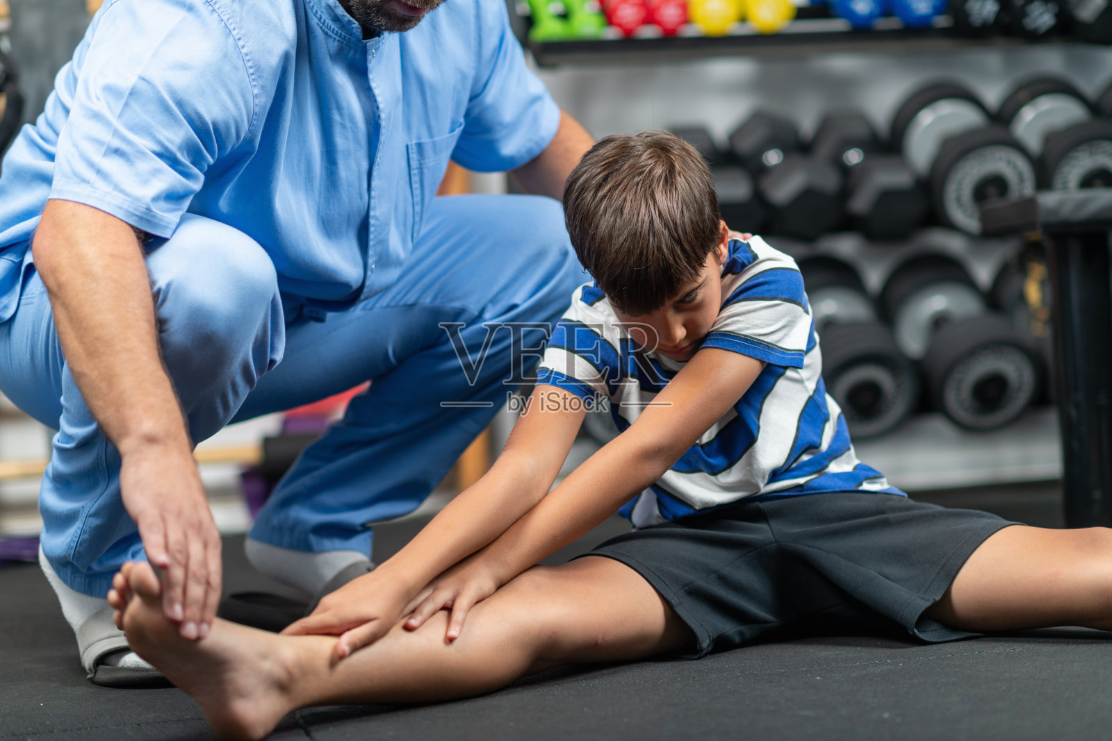 物理治疗师在个性化康复课程中指导一名年轻男孩进行锻炼，重点改善他的灵活性、力量和平衡。照片摄影图片