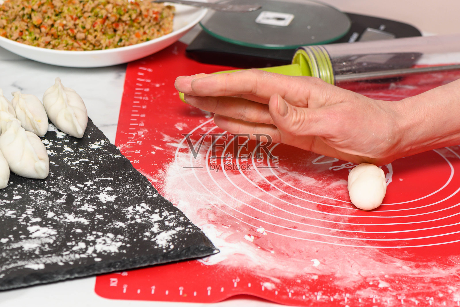 一位女性在厨房里用面团雕刻肉馅饺子。制作美味的自制饺子。照片摄影图片