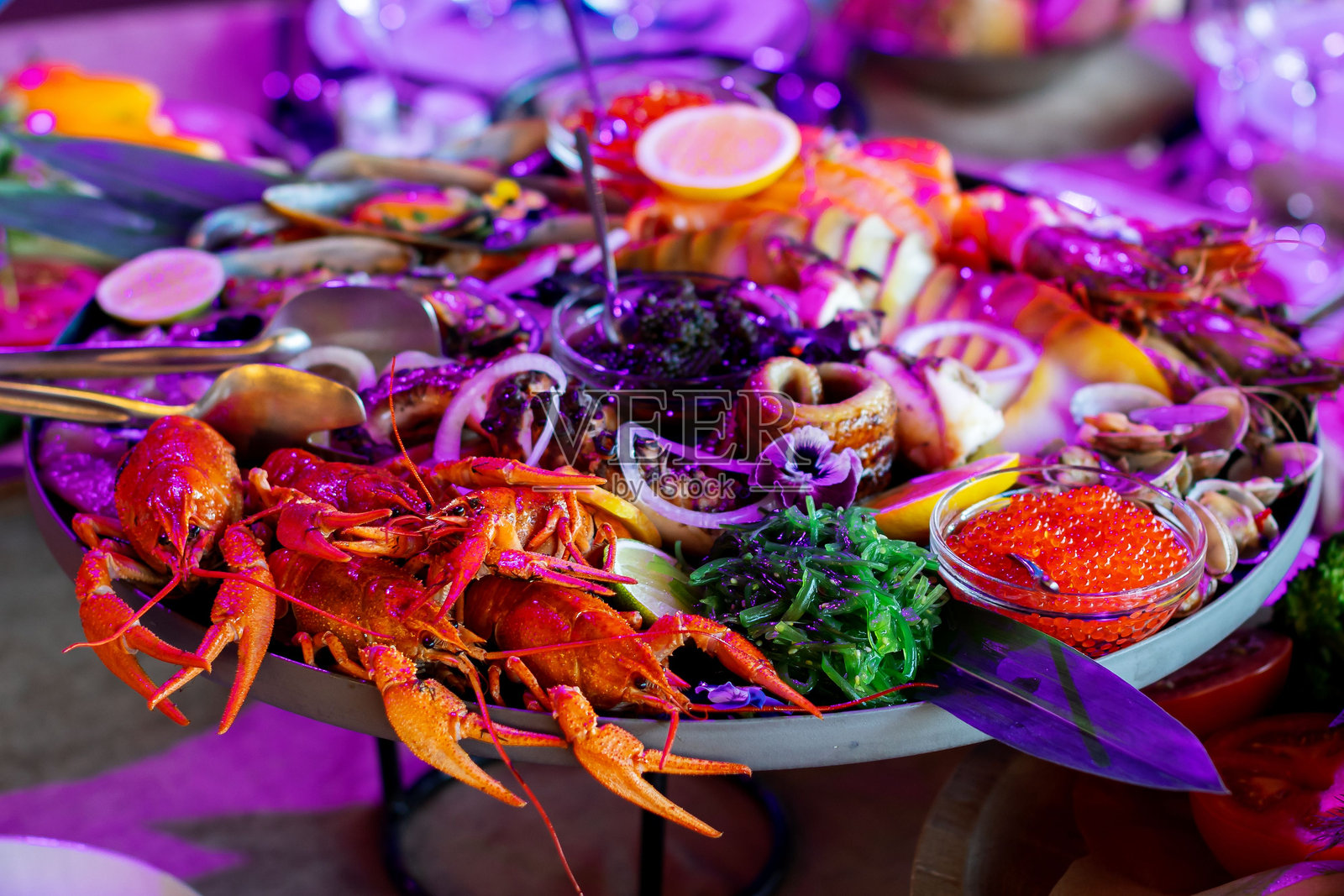 圆盘中盛放各种海鲜和酱汁的特写镜头，背景模糊。照片摄影图片