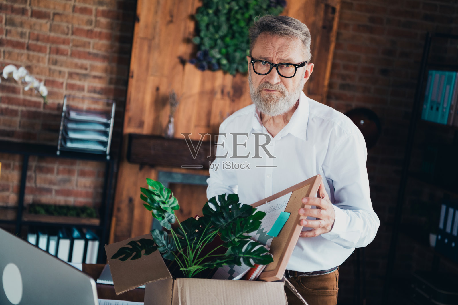 穿着白色衬衫的帅气成熟男士在现代办公室室内的纸箱旁被解雇照片摄影图片