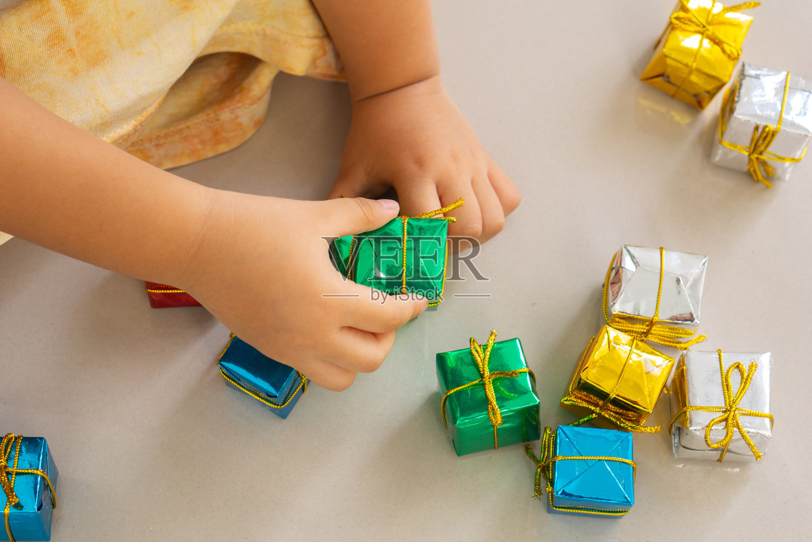 女儿的手在地板上玩圣诞礼物盒的特写。照片摄影图片
