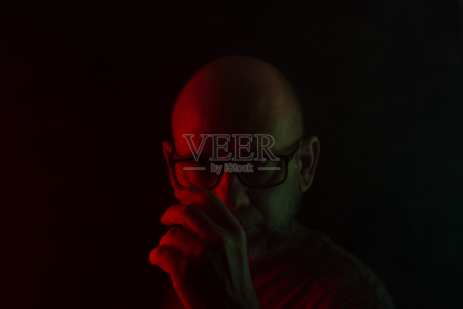 光滑的秃头和胡须男子戴着处方眼镜的特写肖像，背景为黑暗烟雾和彩色灯光。照片摄影图片