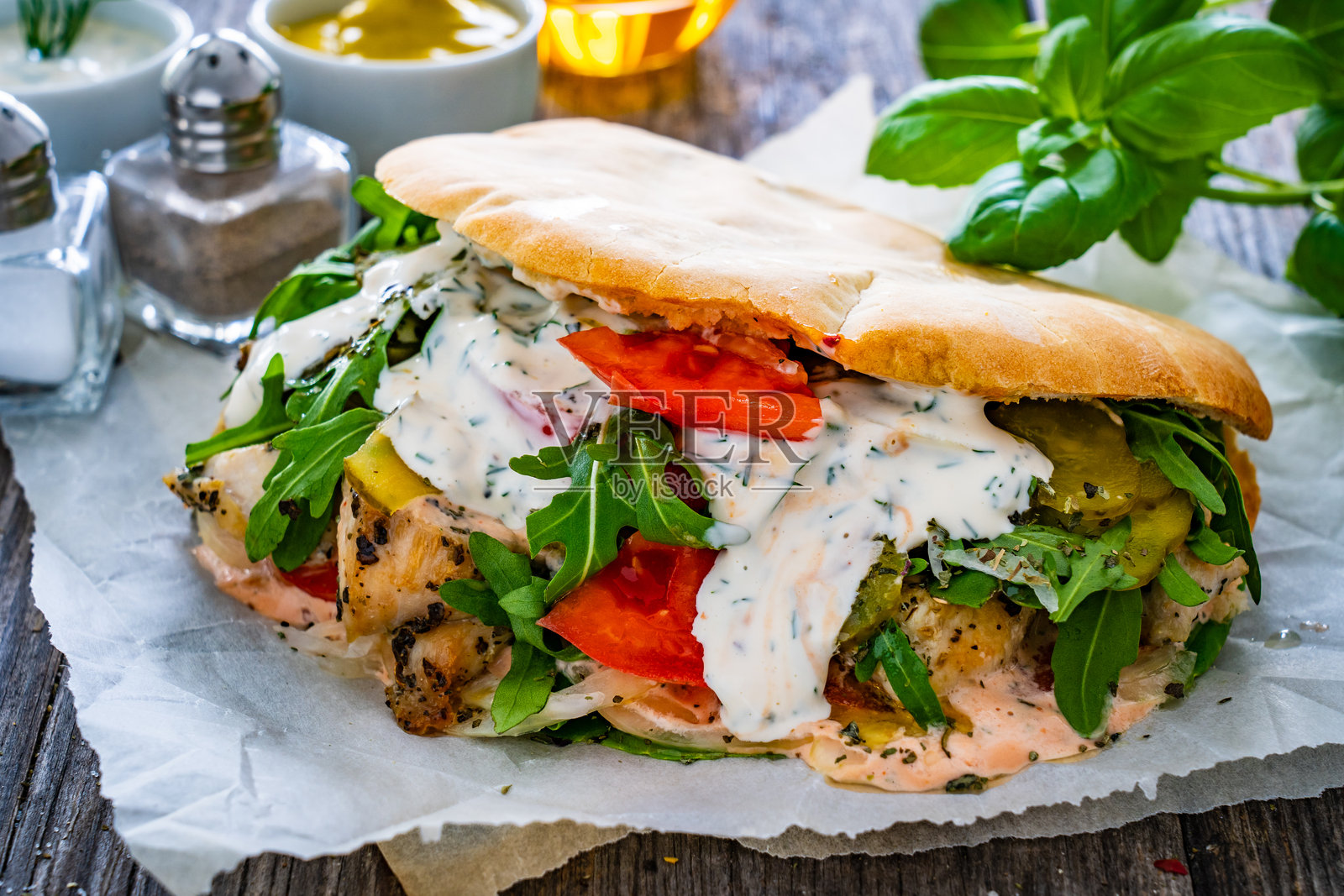 皮塔饼 - 大三明治，夹有鸡块和新鲜蔬菜，放在木桌上照片摄影图片