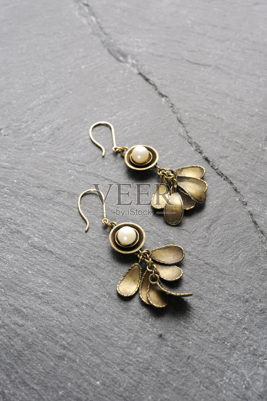 黑色石板上的珍珠黄铜耳环照片摄影图片