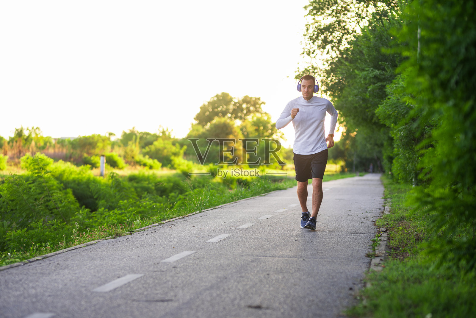 年轻运动员戴着耳机在公园里跑步照片摄影图片