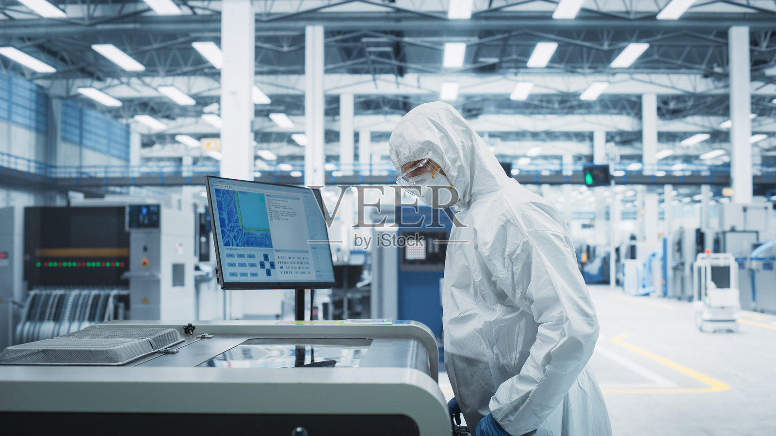 电子工厂的印刷电路板生产：技术人员穿着无尘服，使用焊接喷墨打印机制造现代中央处理器主板。计算机硬件制造设施。照片摄影图片