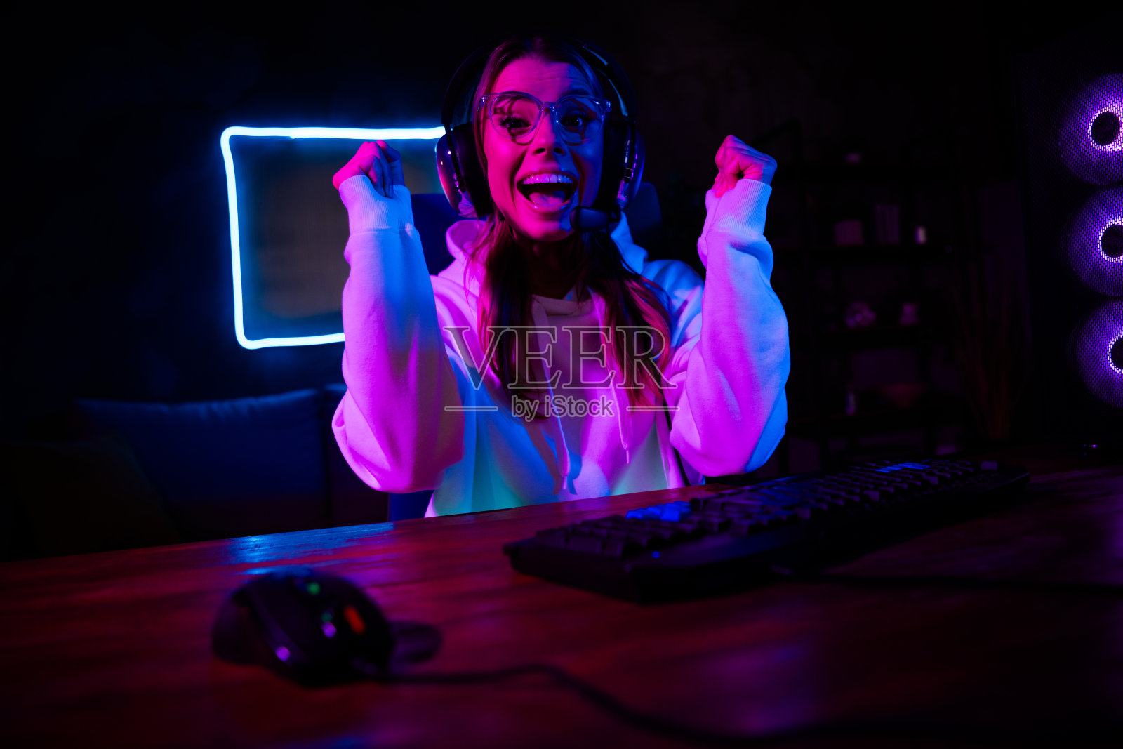 年轻女性在霓虹灯下享受充满活力的游戏时光，体现了数字世界中的乐趣与兴奋。照片摄影图片
