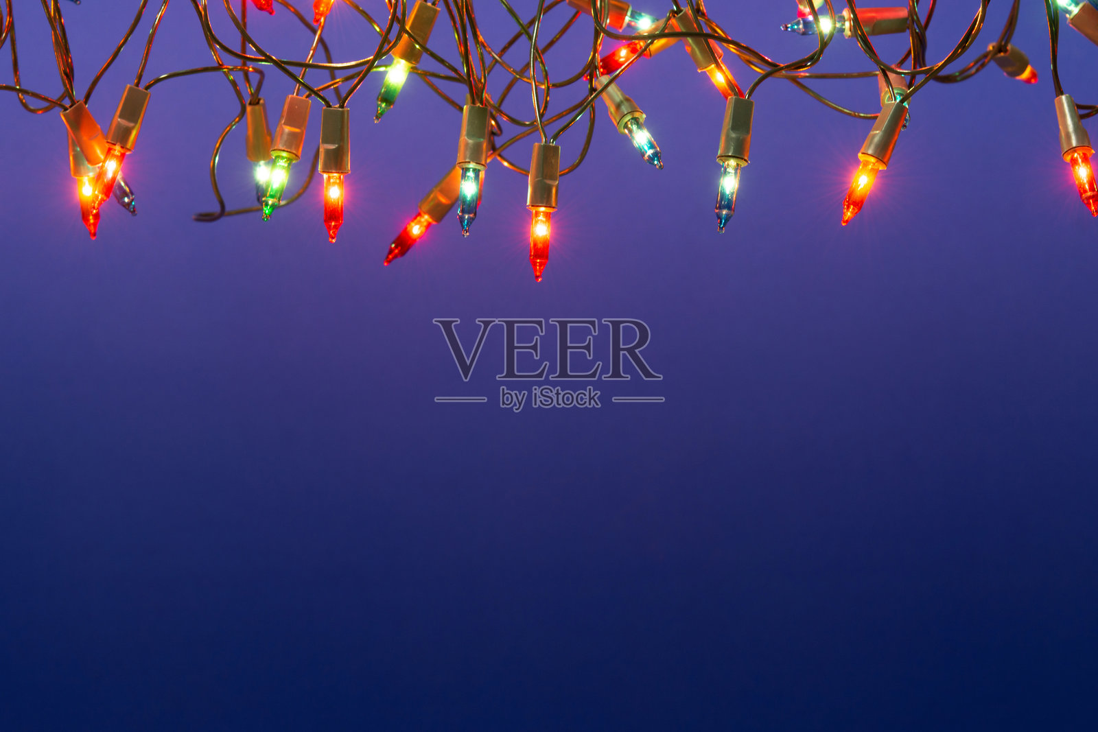 蓝色背景上的圣诞灯串，留有空白空间照片摄影图片