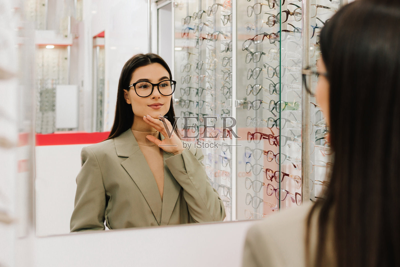 女性在购物中心的眼镜店试戴和选择眼镜。她在光学商店挑选透明镜片的眼镜。照片摄影图片