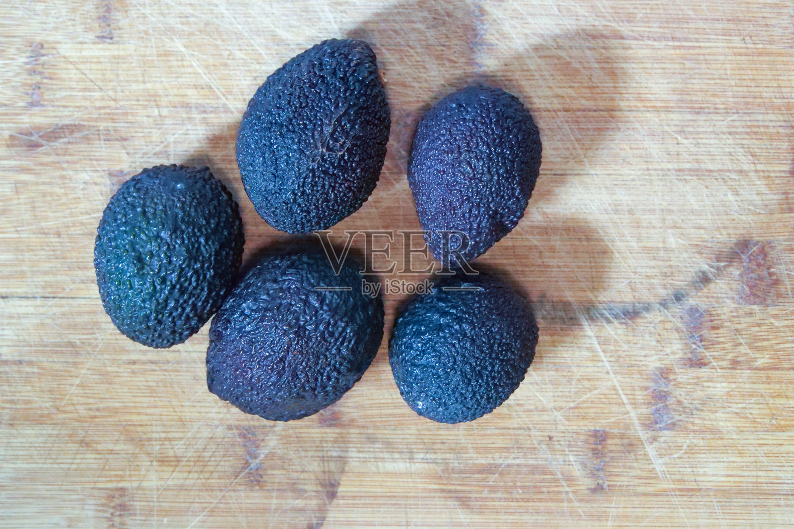 五个鳄梨放在棕色木质背景上。照片摄影图片