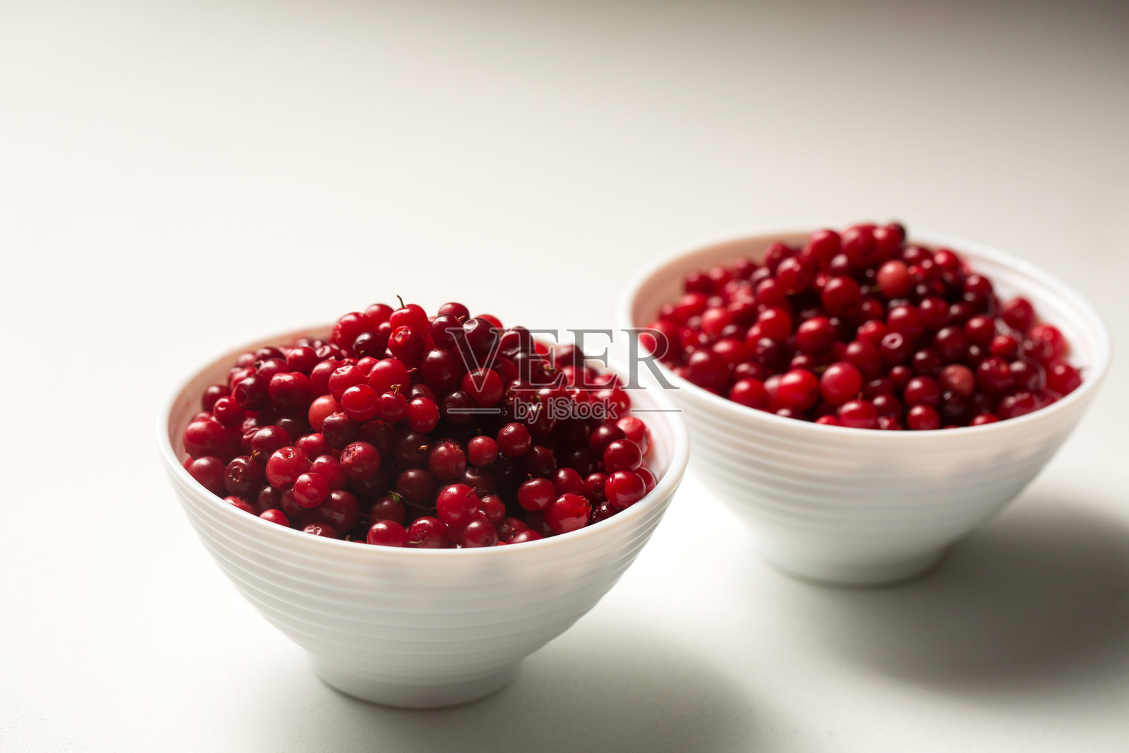 两碗红色越橘放在白色背景上照片摄影图片