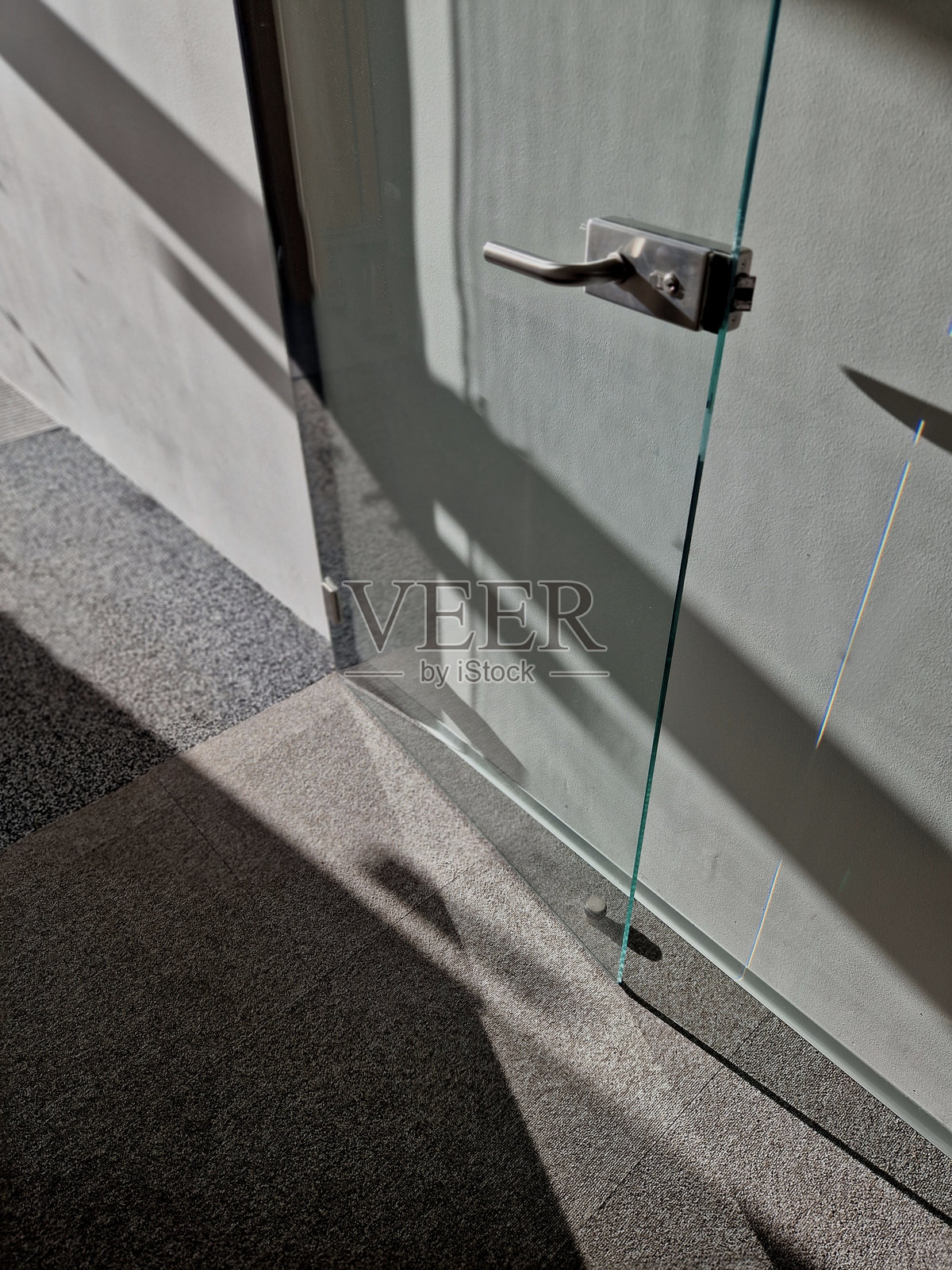 办公室的玻璃门上有一个橡胶不锈钢止挡，保护墙壁和门把手免受撞击。照片摄影图片