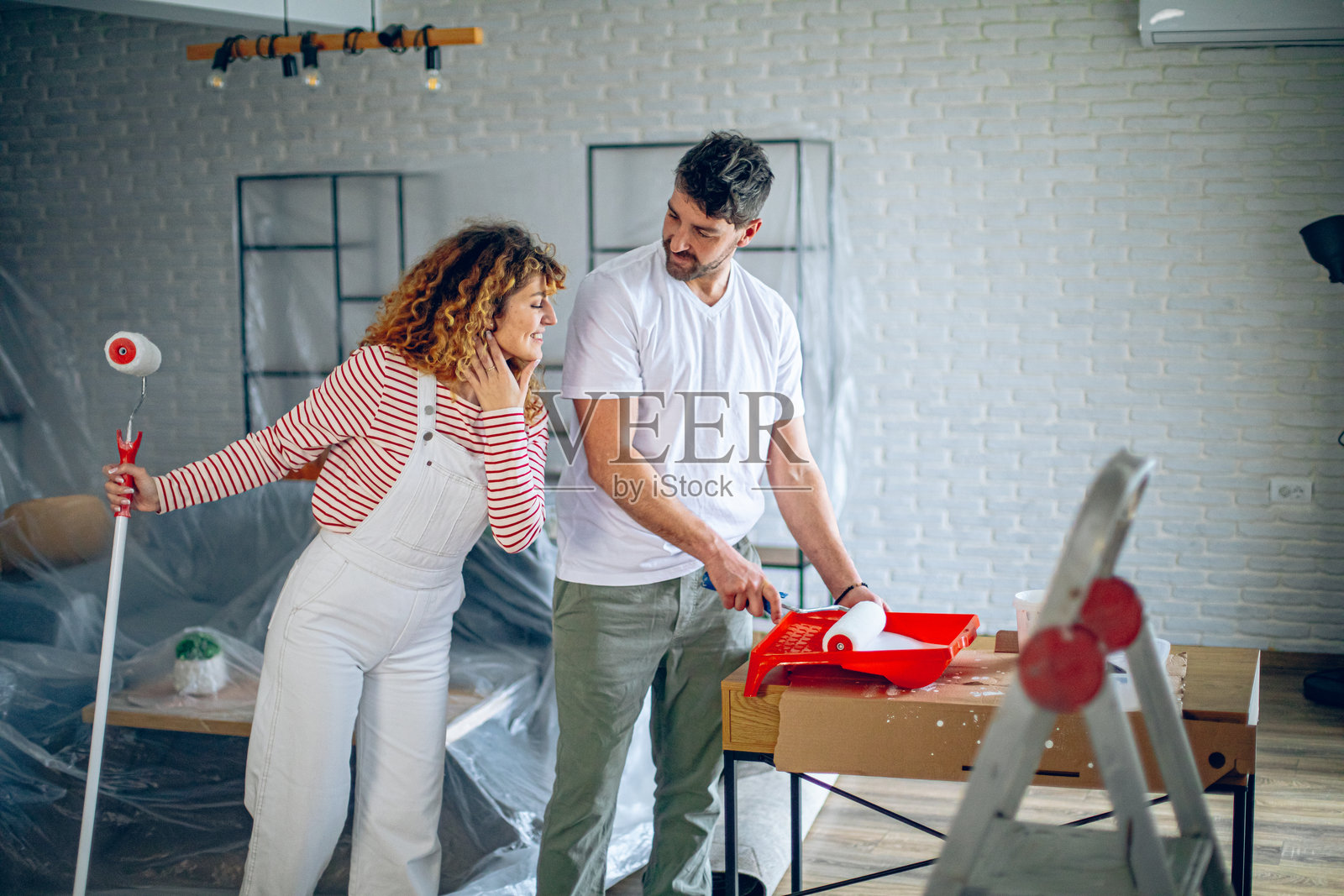 快乐的情侣在家中涂墙时享受乐趣照片摄影图片