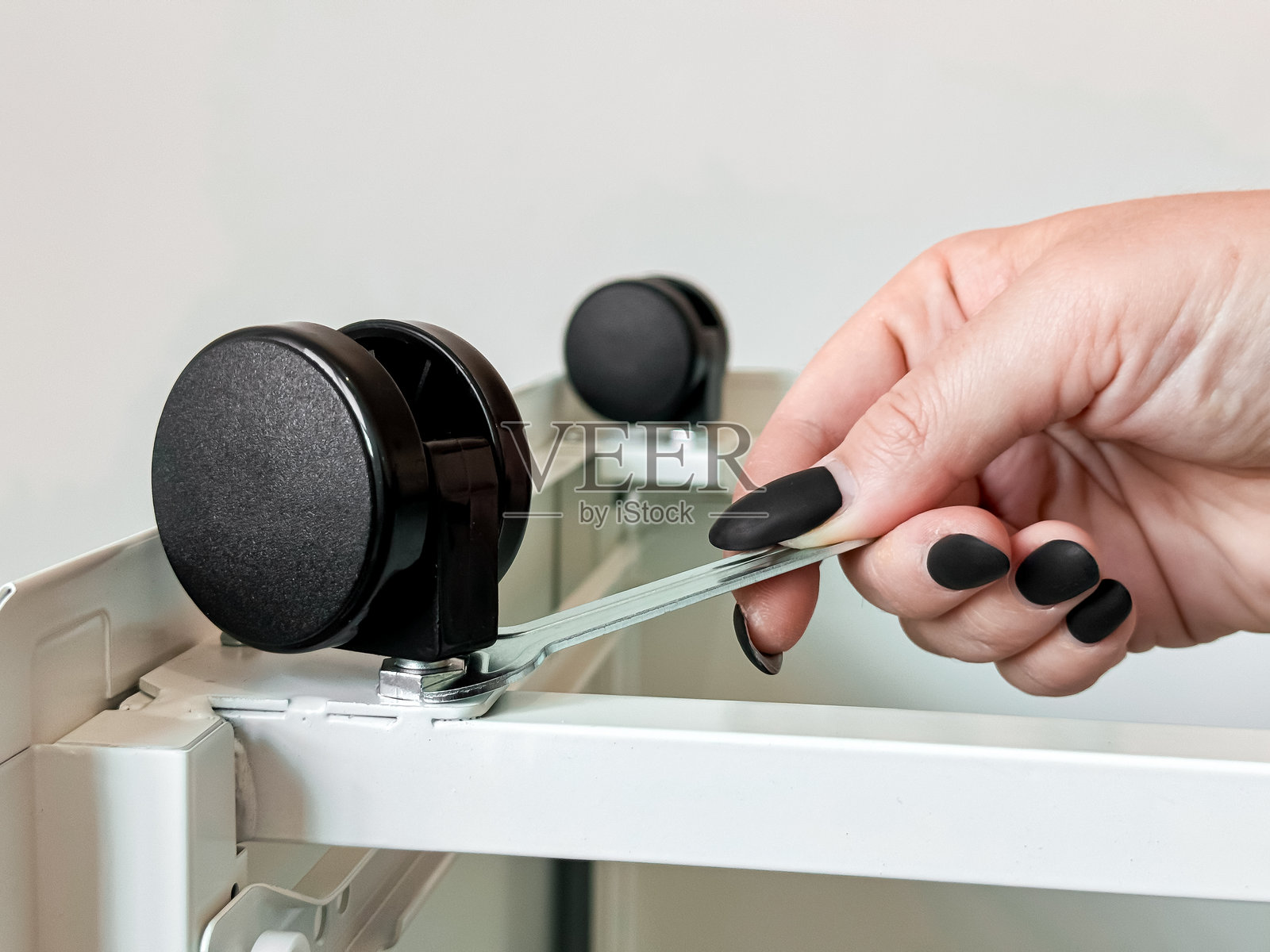 女性手用扳手调整办公家具的脚轮照片摄影图片