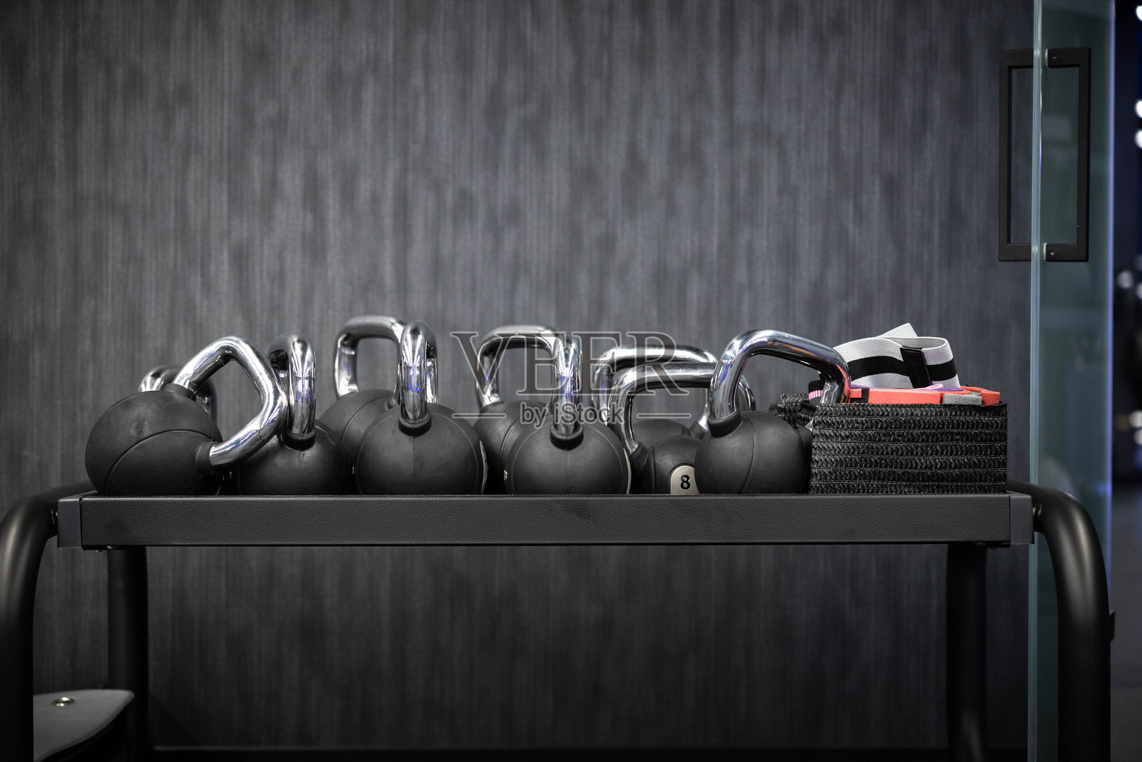 现代健身房装饰中的一排壶铃放在架子上照片摄影图片