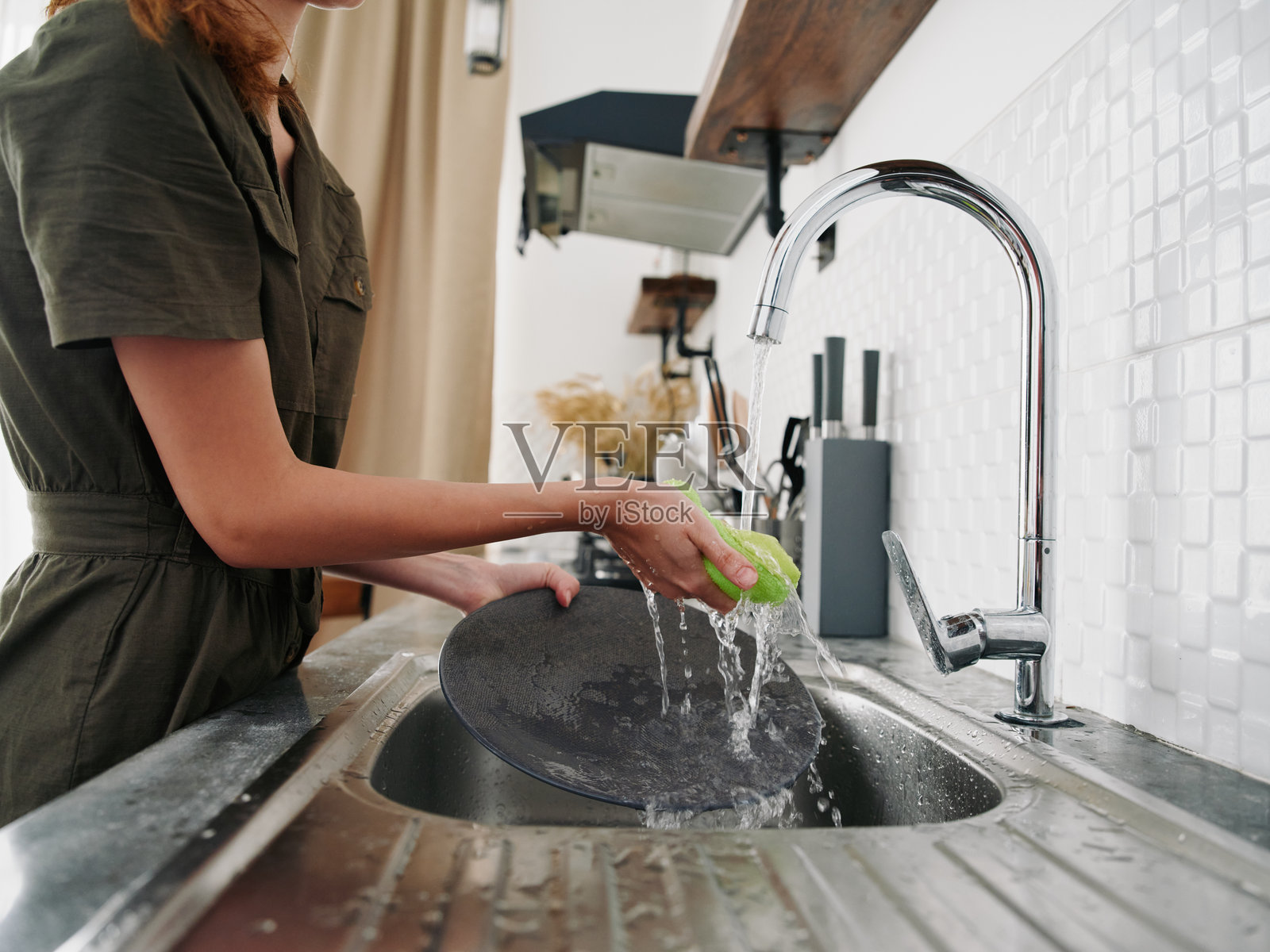 没有戴手套的女性用洗碗海绵洗碗，家务活，没有洗碗机，高水消耗。手部特写。照片摄影图片