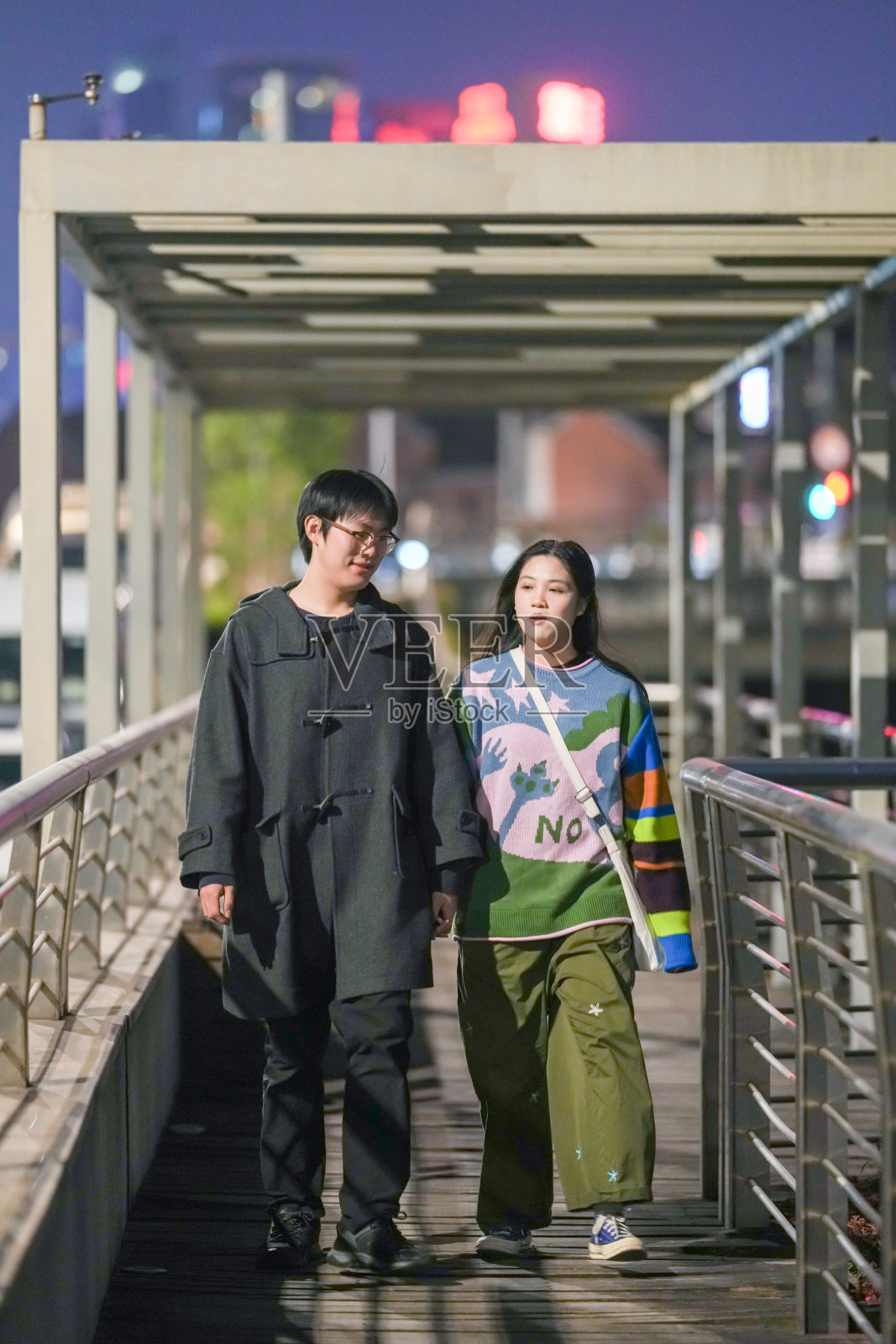 一对二十多岁的年轻中国情侣在2024年12月1日的寒冷季节，沿着上海虹口区外滩的河边人行道散步。照片摄影图片