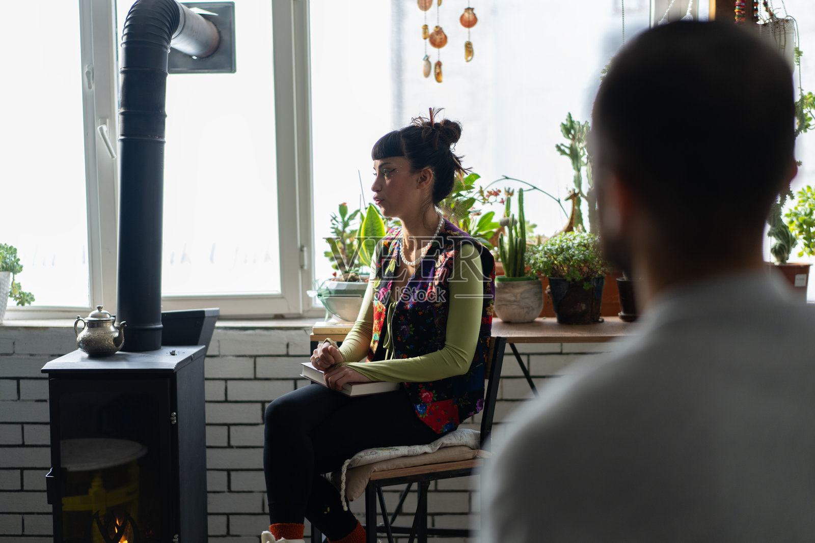 在温馨的房间里，女人在会议上发言，旁边有一个木炉。照片摄影图片