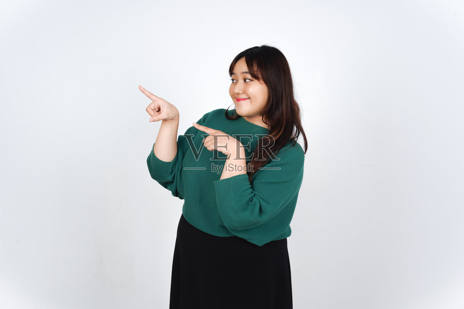 微笑的亚洲女性在白色背景上展示并指向旁边的广告空白处，展示产品。照片摄影图片