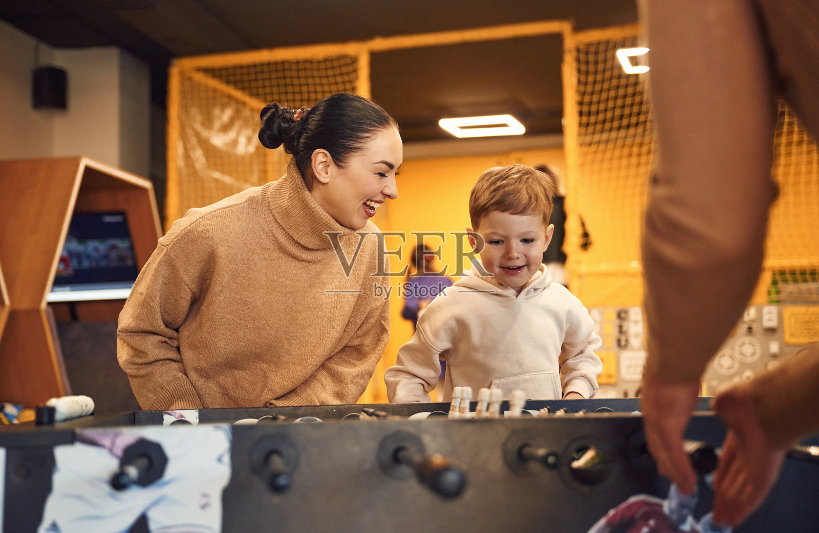 快乐的家庭：爸爸、妈妈和儿子在室内玩桌上足球游戏照片摄影图片